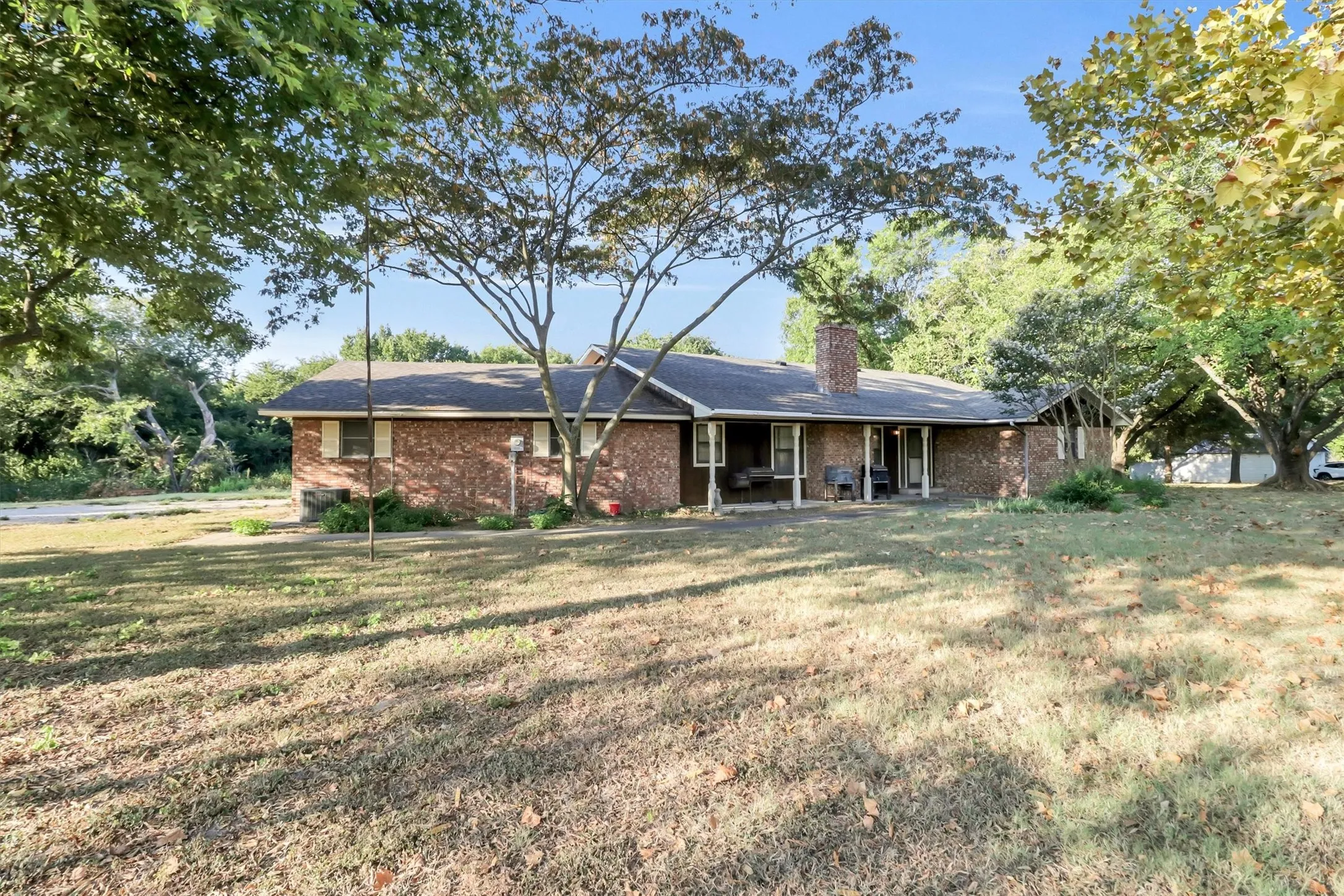 Brick exterior residence featuring an expansive front lawn and mature trees
