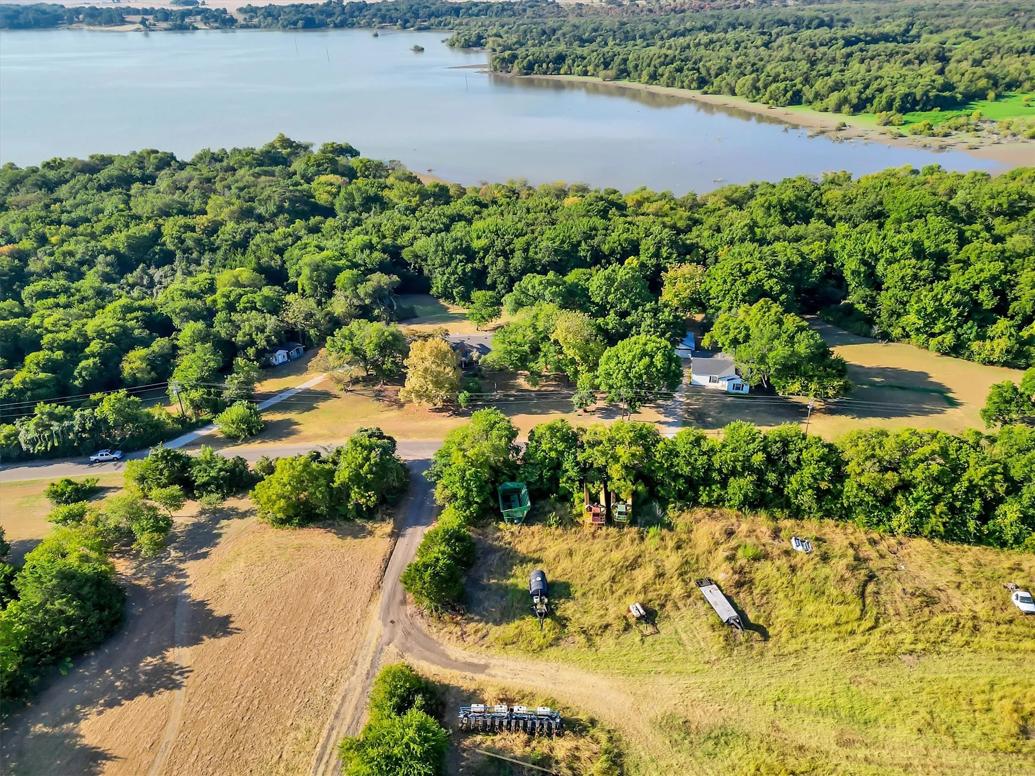 Expansive land parcel with direct lake frontage, mature trees, and a residential structure