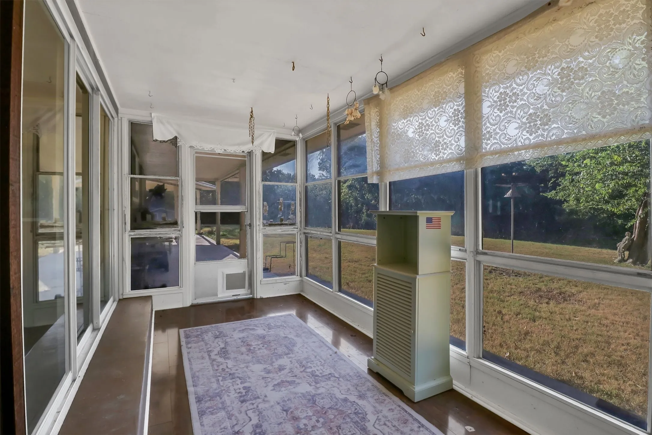 Enclosed sunroom featuring numerous window panels, a white ceiling, and dark-finish flooring