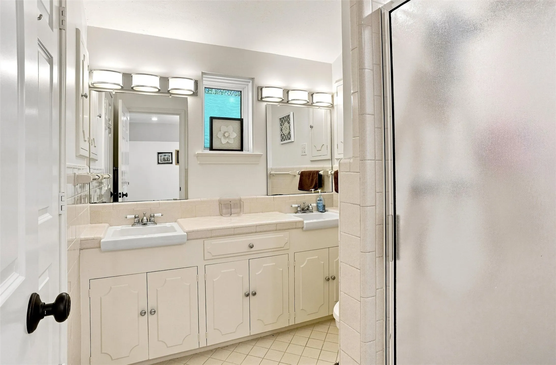 This is the ensuite bath arrangement for the SECOND PRIMARY bedroom.  A full bath with double sinks and shower. This room has been kept in sync with the Mid-Century Modern home.