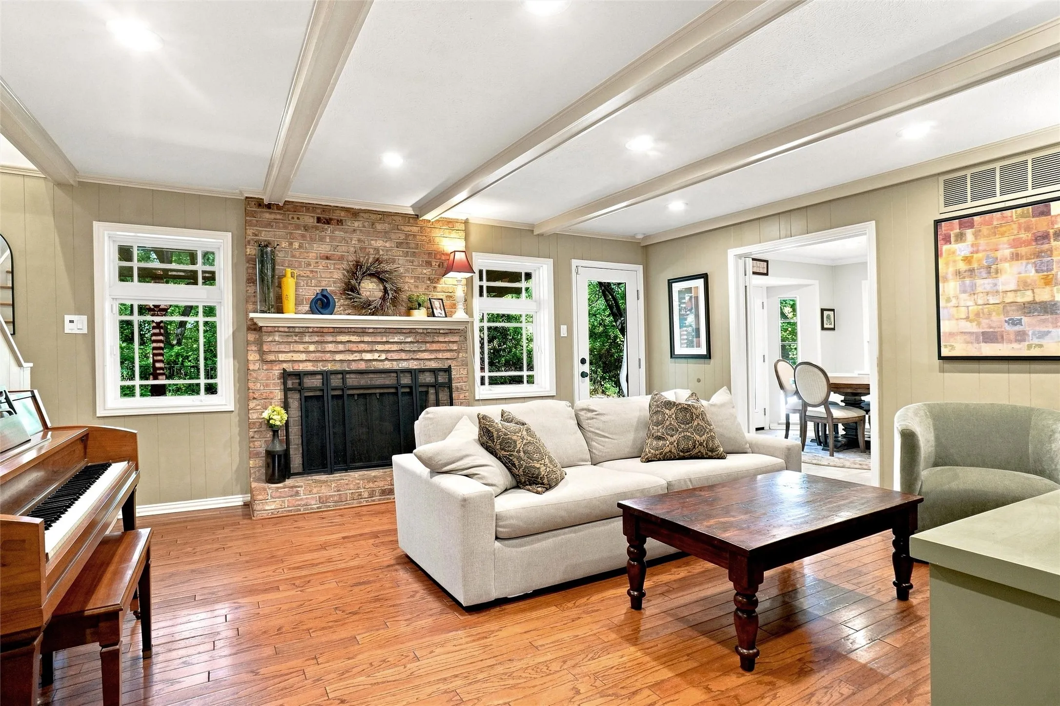 To the rear of the home is the family room with a beautiful beamed ceiling, lovely windows and a stately wood burning fireplace.  All of the exterior doors have been replaced.  The wood floors also flow through this room.  The designer paint selections are just absolutely beautiful and just spot on!