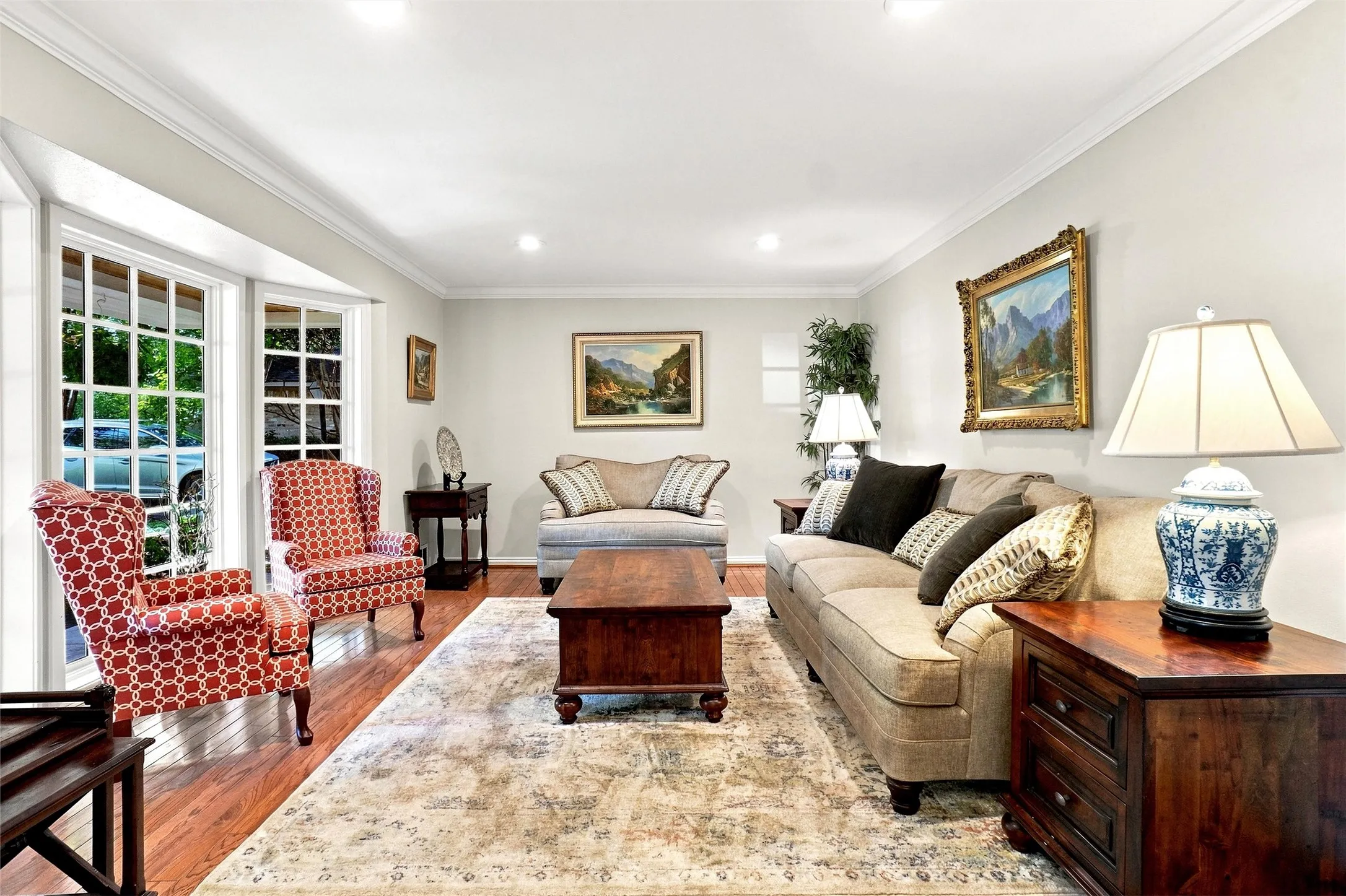 The living room to the front of the home is graced with floor...to nearly ceiling windows that help bring the outdoors in!  Crown molding, recently added recessed LED lighting, and rich hardwood flooring help make this versatile area a very welcoming addition to any home.