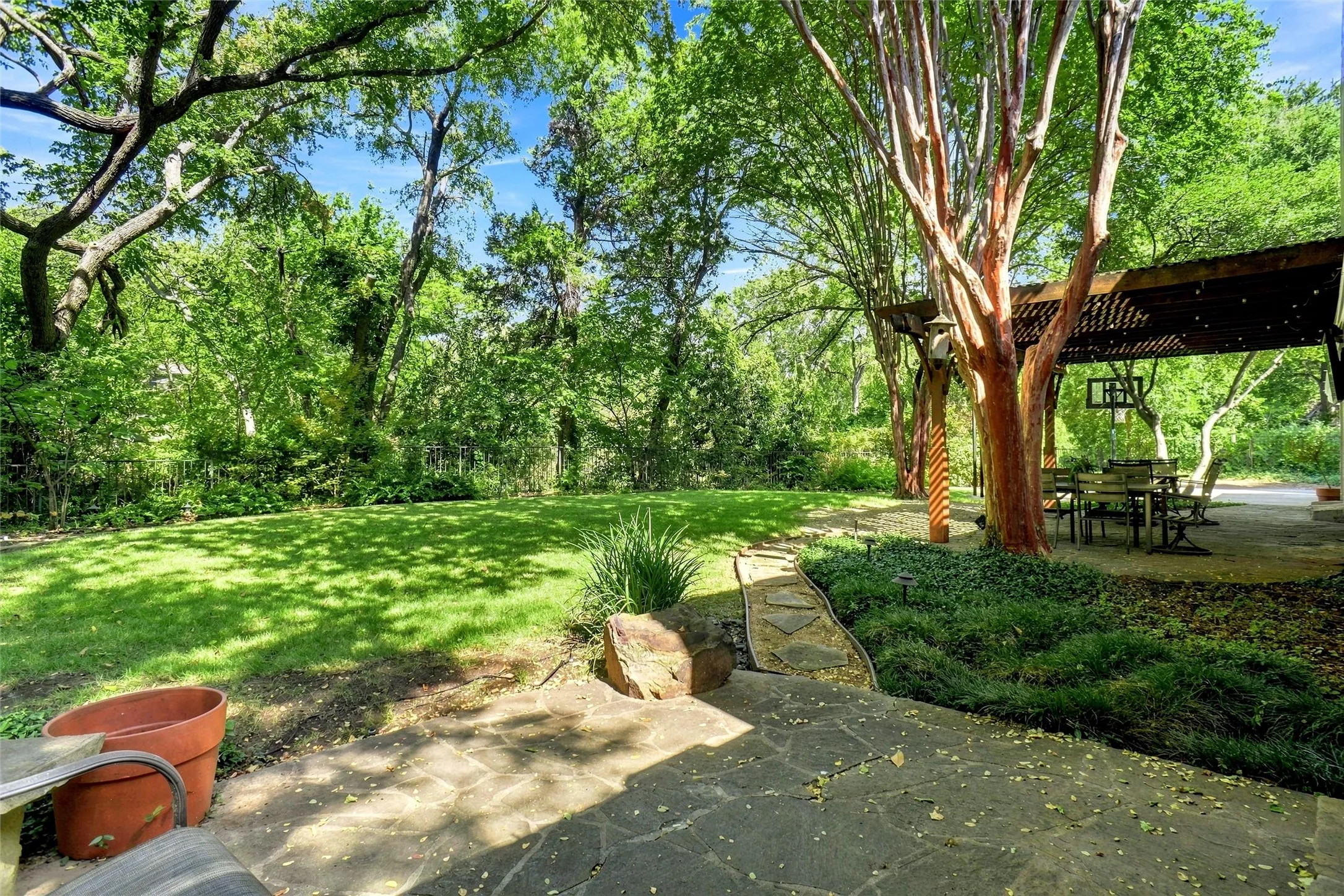 You can see all of the NATURAL BEAUTY!!!!  This is such a relaxing hide away. Gorgeous trees and landscaping, a pergola covering a flagstone patio, and additional flagstone open patio with walkways.  Also a lush beautiful lawn. The tree line has  wrought iron fencing that encloses the rear yard. Also an electric gate to the rear car garage.   What natural beauty!