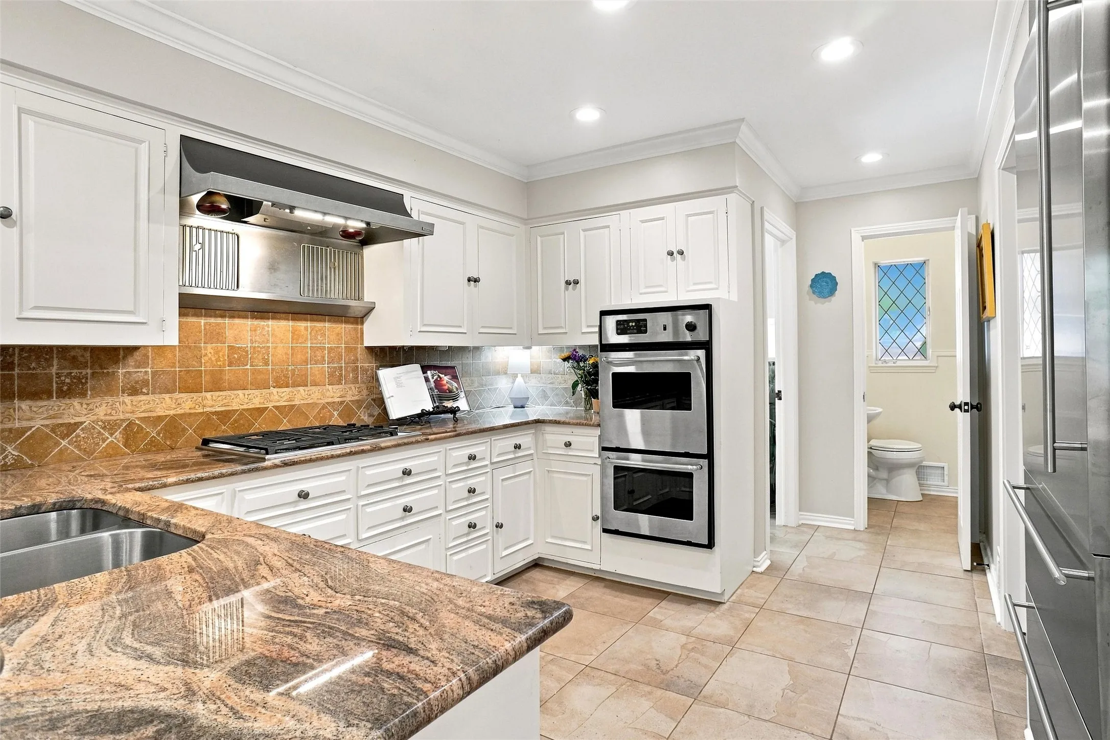 The kitchen has a gas cooktop, a warming shelf, a Miele Dishwasher, a gas Wolfe stove, an oversized built-in custom Liebherr fridge-freezer unit, and a  double oven.