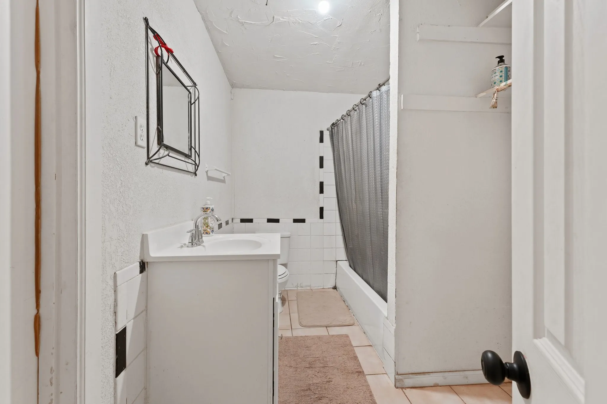 Bathroom featuring a white vanity with integrated sink, chrome faucet, and tiled shower area