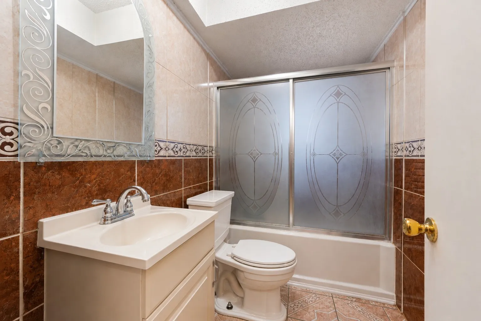 Built-in vanity with integrated sink, chrome faucet, decorative framed mirror, and a tiled shower with sliding frosted glass doors