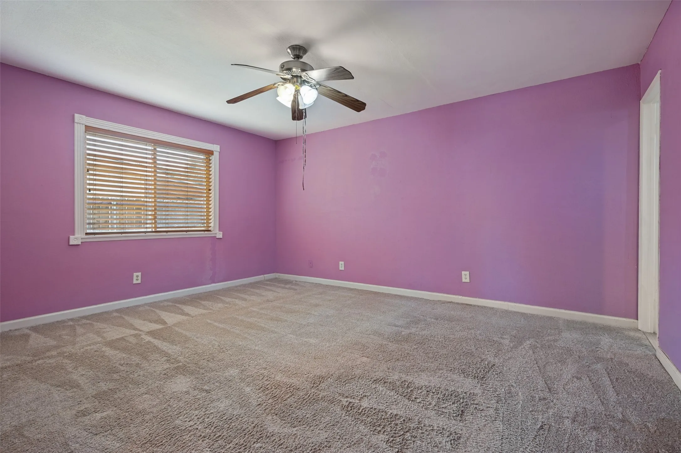 Recessed window with wood-finish blinds, ceiling fan with integrated lighting, and neutral-toned carpeting throughout