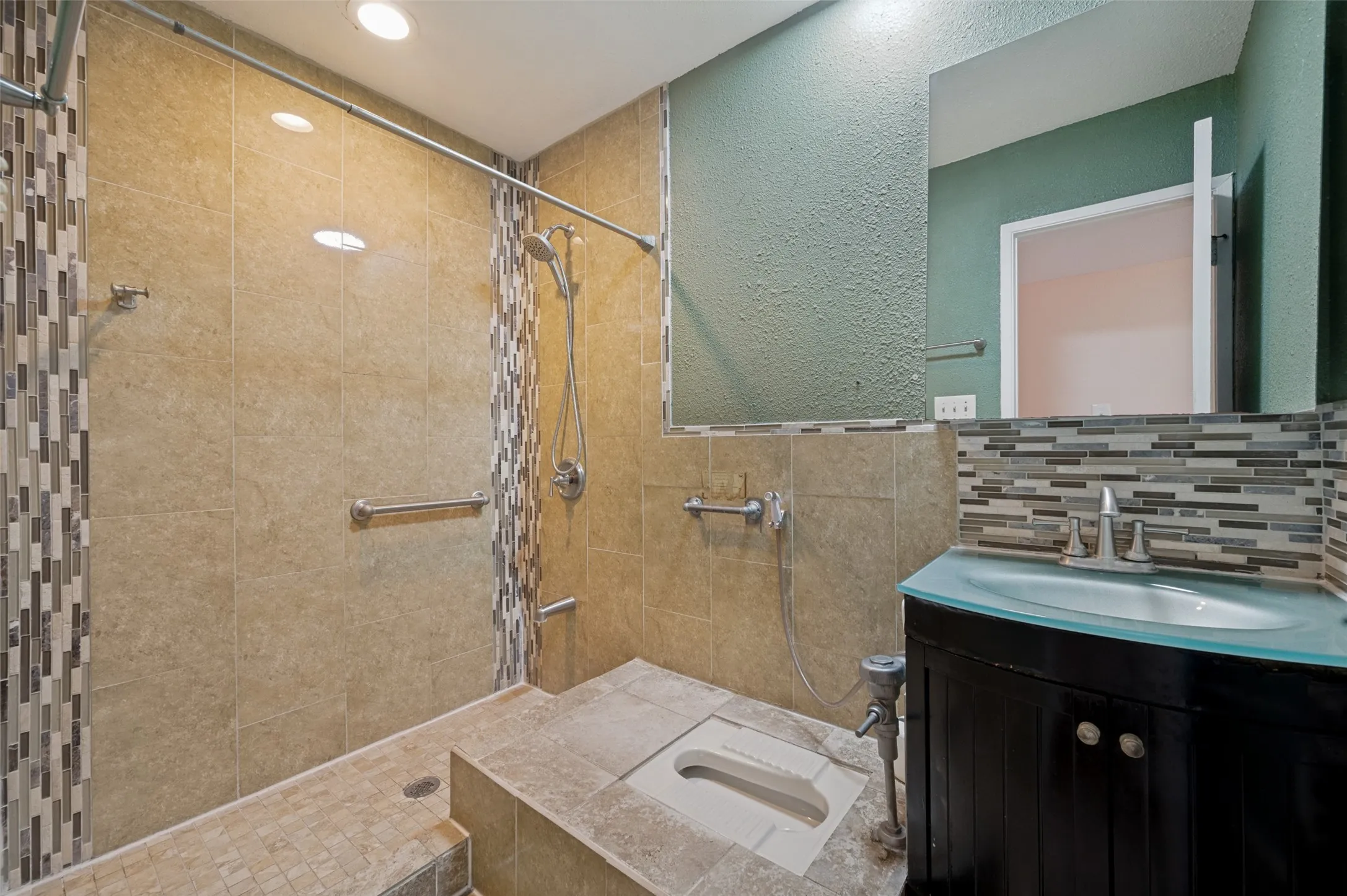 Walk-in shower with natural stone-look tile, mosaic accent tile, and multiple grab bars