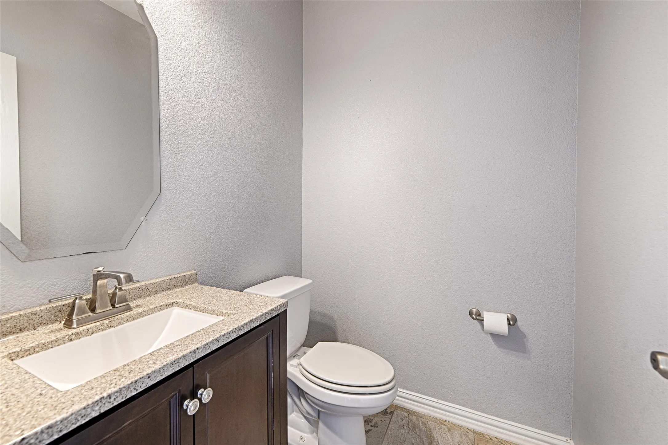 Vanity with granite-style countertop, undermount sink, and brushed nickel faucet