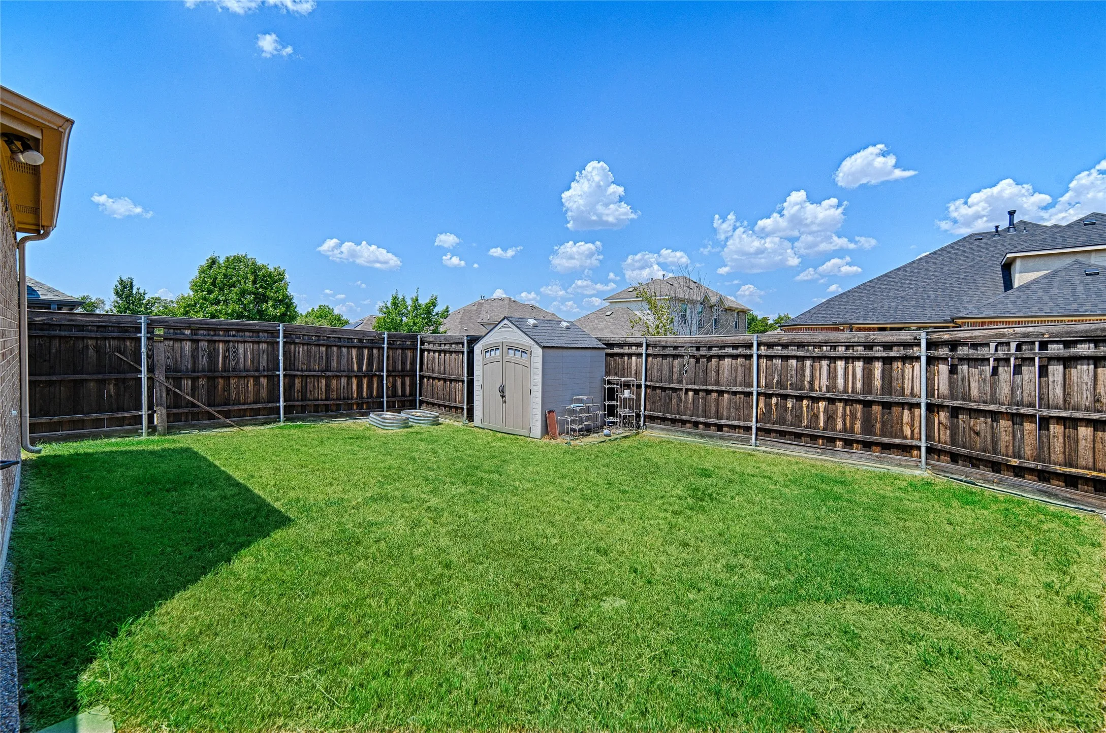 Expansive green lawn, wood privacy fencing, and an included storage shed
