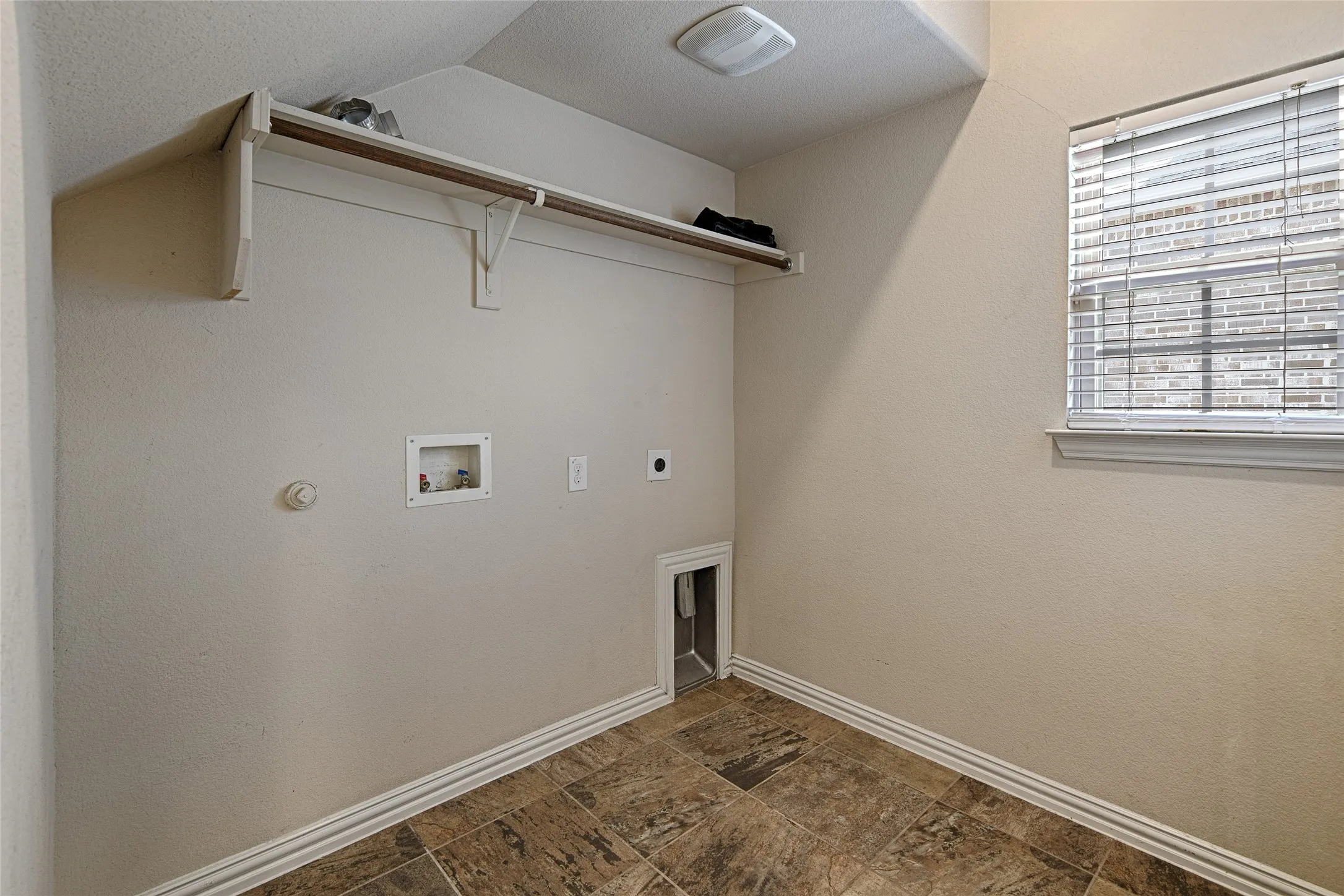 Dedicated utility room featuring wood-finish flooring, a built-in shelving unit with a hanging rod, and a window with blinds