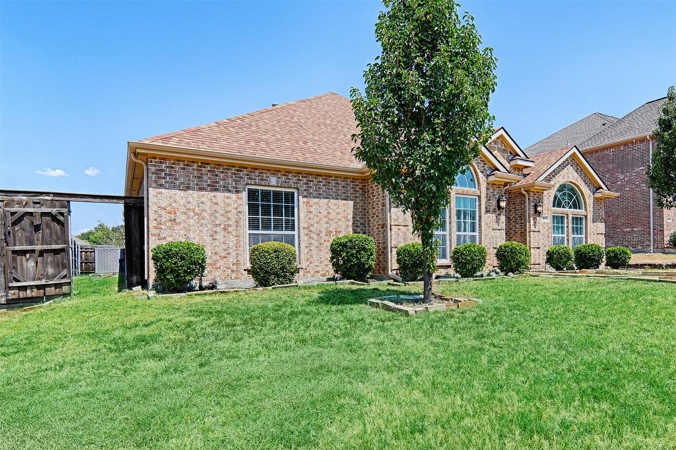 Brick exterior featuring arched windows, accent gables, and a mature tree
