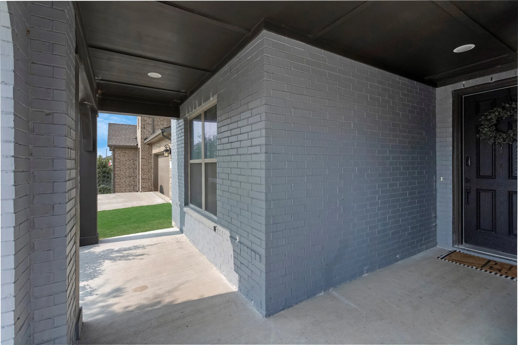 Covered entryway featuring painted brick exterior, concrete flooring, and recessed lighting