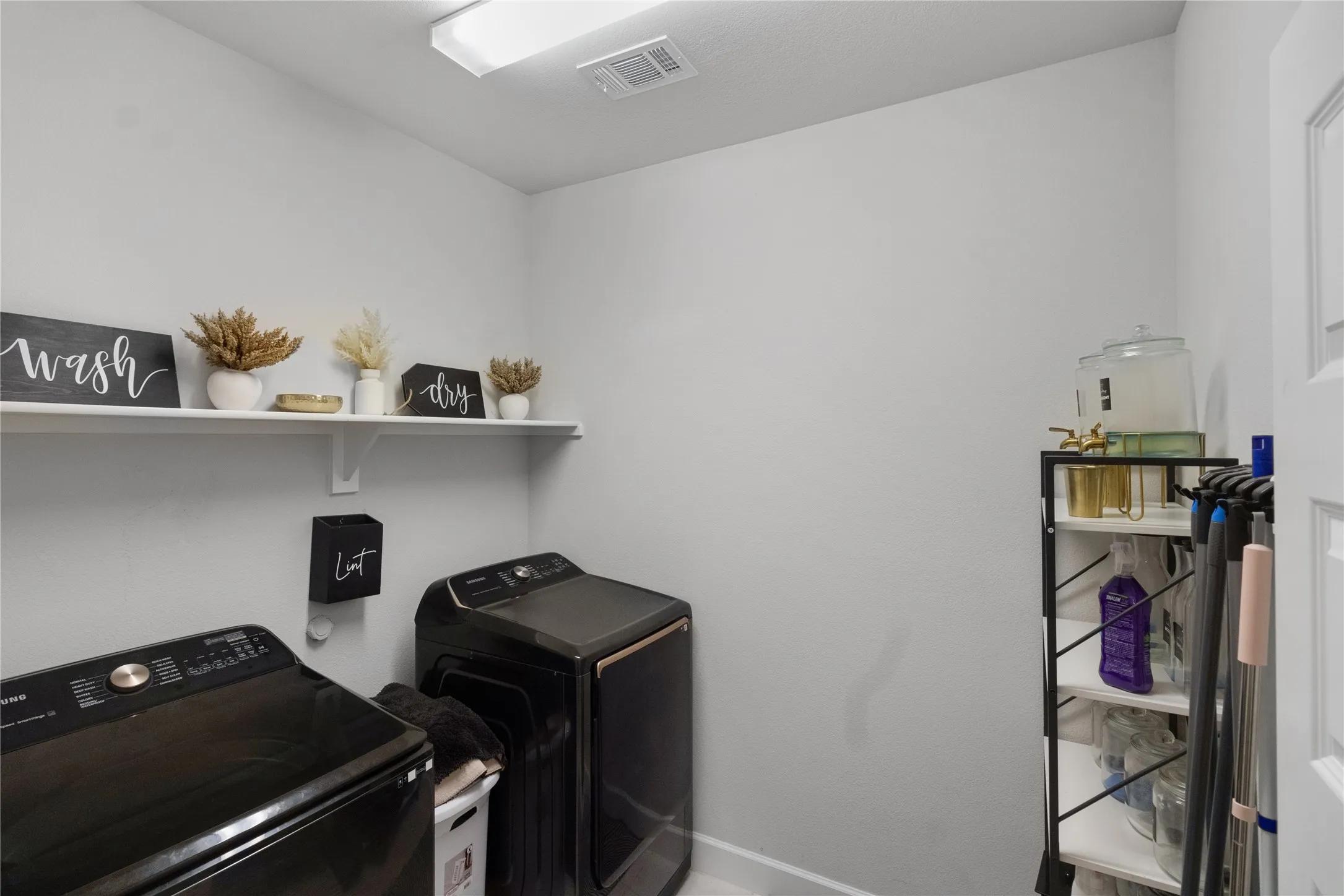 Dedicated utility room with a wall-mounted shelf and overhead lighting