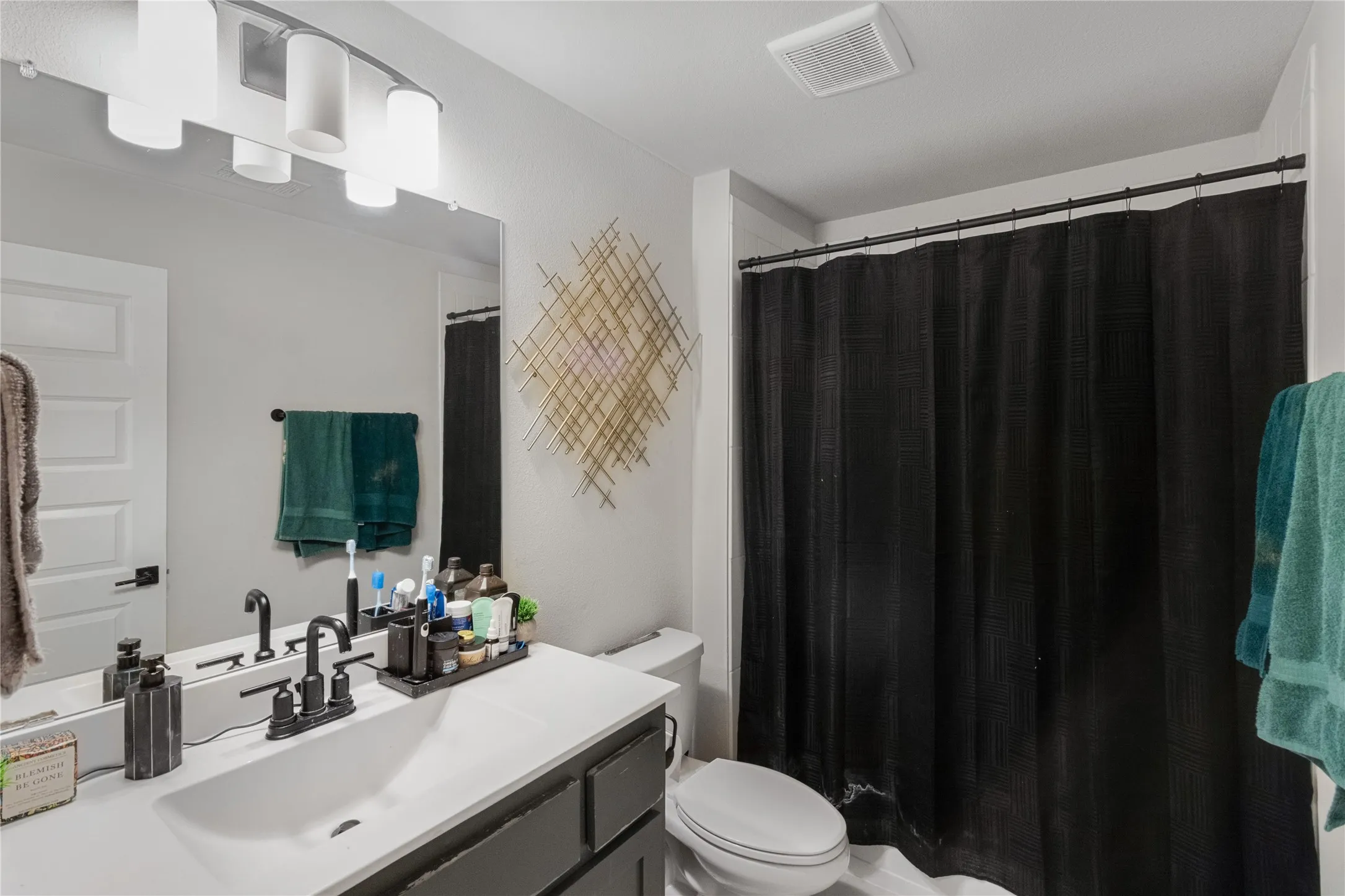 Vanity with white countertop and integrated sink, matte black faucet, wall-mounted mirror, and white paneled door