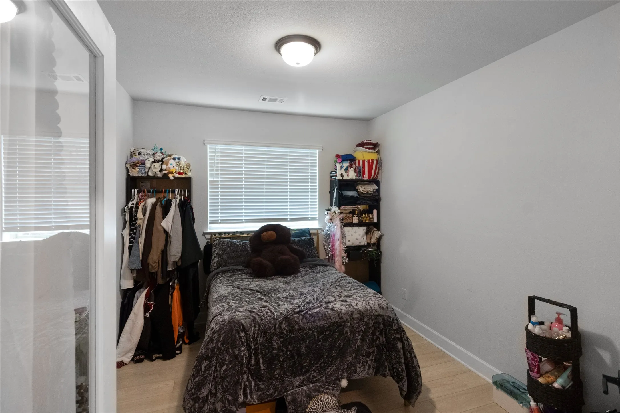 Bright room featuring a window with blinds, wood-finish flooring, and a ceiling-mounted light fixture