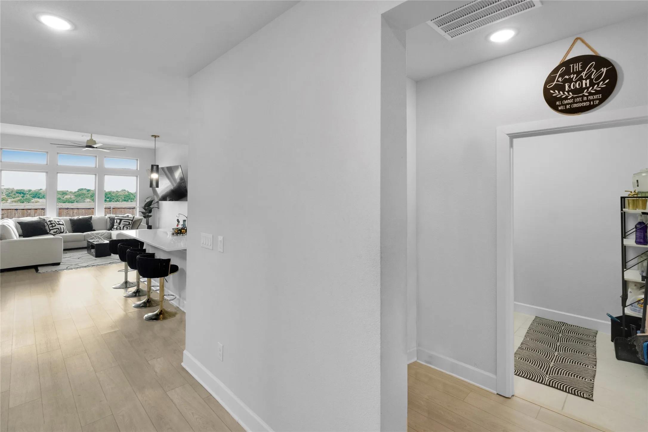 Open-concept living area with wood-finish flooring, recessed lighting, and a breakfast bar with a white countertop