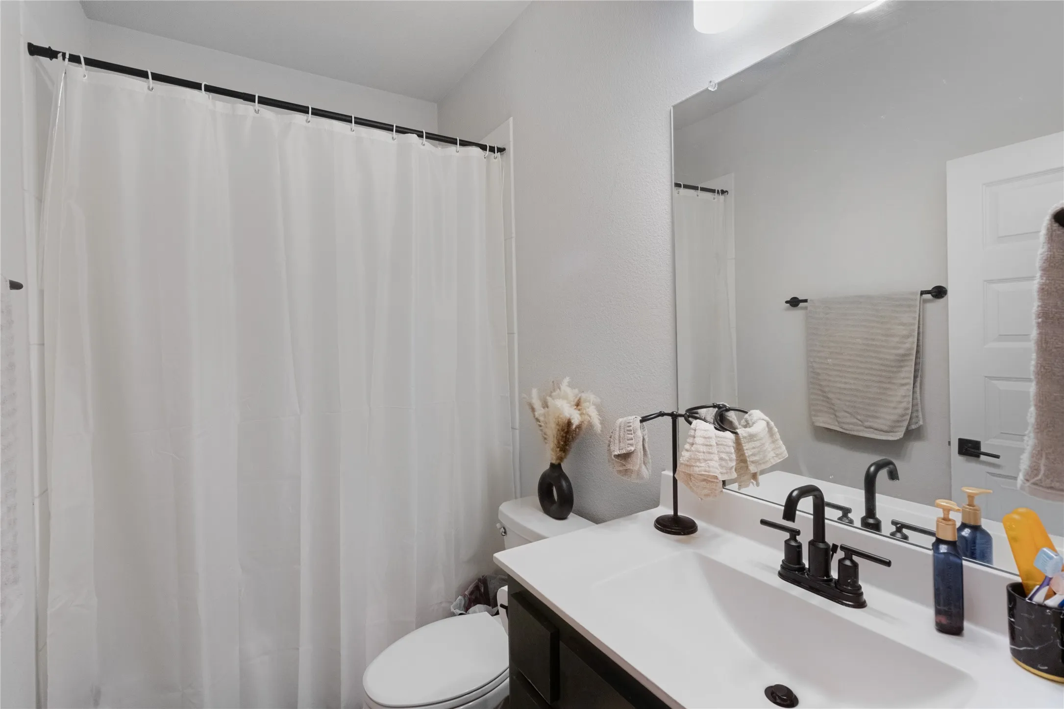 Bathroom featuring a vanity with an integrated sink, matte black faucet, and a large wall-mounted mirror
