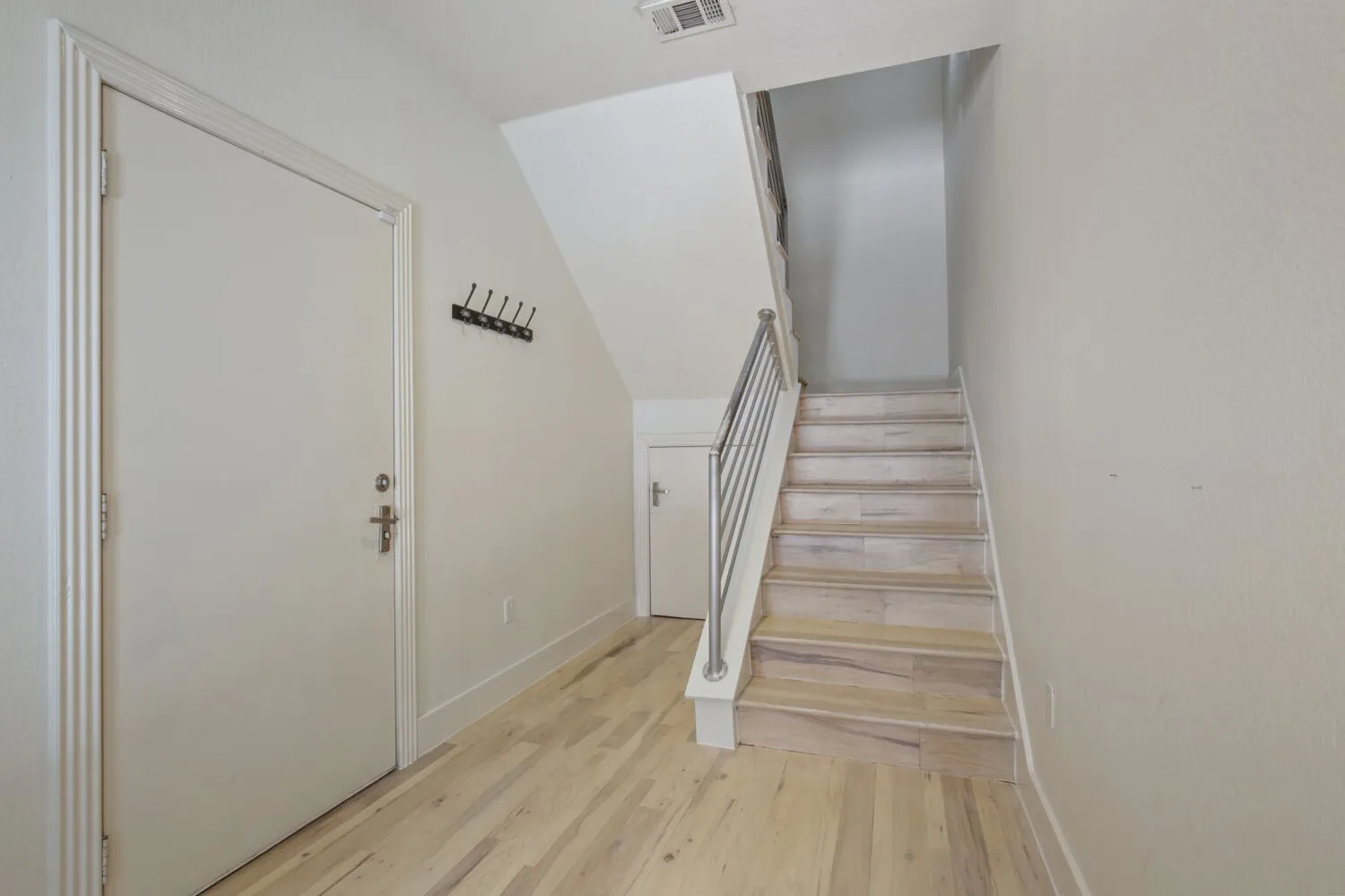 Light wood-finish flooring, staircase with wood-finish treads, and a contemporary metal railing