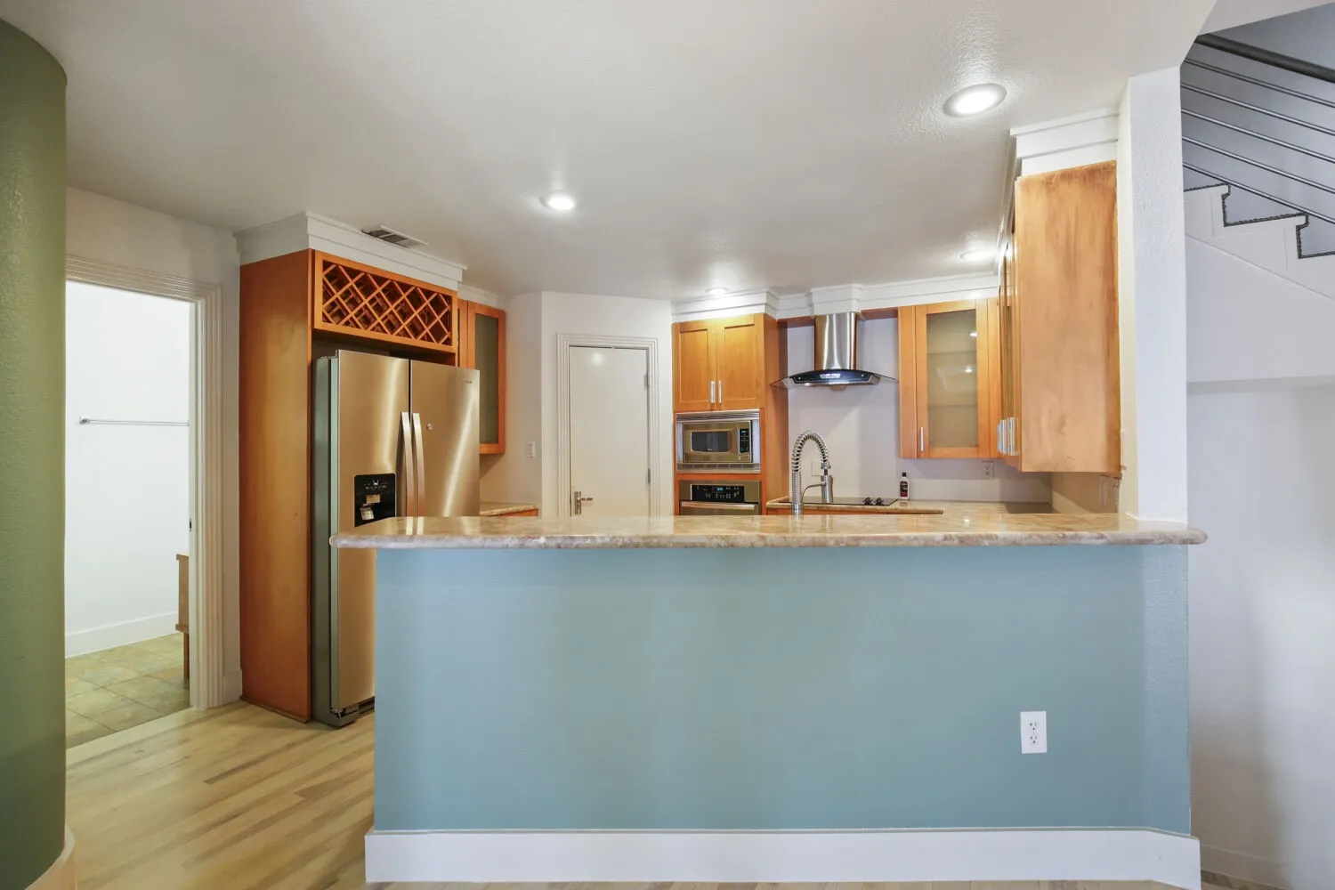 Kitchen featuring wood-finish flooring, stainless steel appliances, light wood cabinetry, stone countertops, and recessed lighting