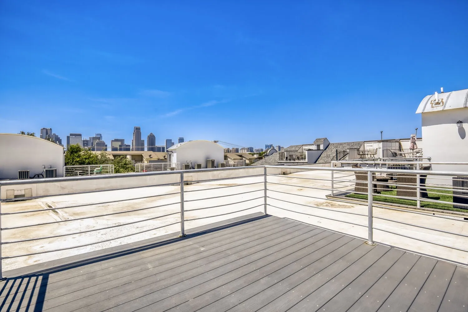 Rooftop deck featuring composite decking, metal railings, and a cityscape backdrop