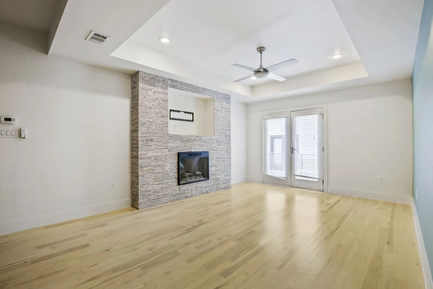 Wood-finish flooring, recessed lighting, ceiling fan, contemporary fireplace, and double French doors with interior blinds