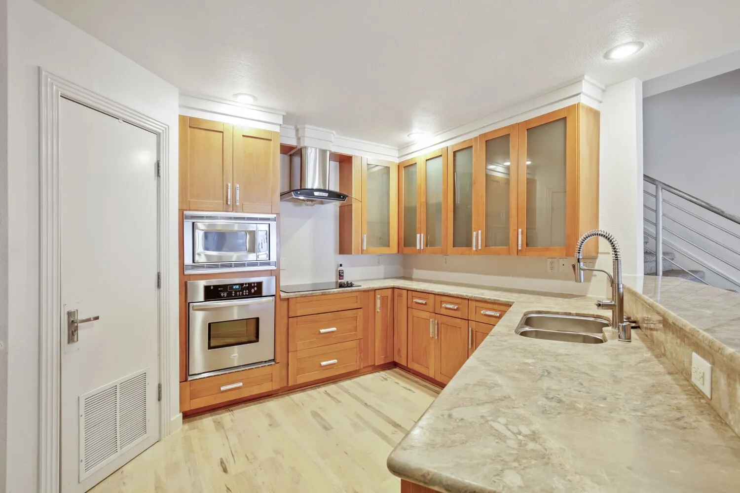 Kitchen featuring light wood cabinetry, stainless steel appliances, dual basin sink, and light stone countertops