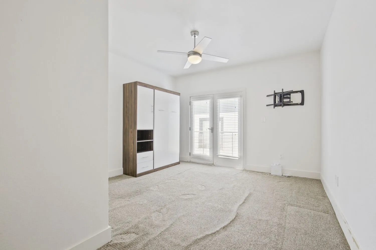 Ceiling fan with integrated lighting, double patio doors with blinds, and light-colored carpeting