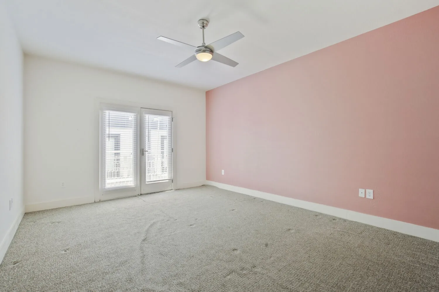Wall-to-wall carpeting, dual glass panel doors with blinds, painted accent wall, and ceiling fan with integrated lighting