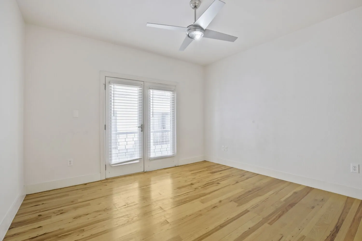 Wood-finish flooring, white walls, and a modern ceiling fan with integrated lighting