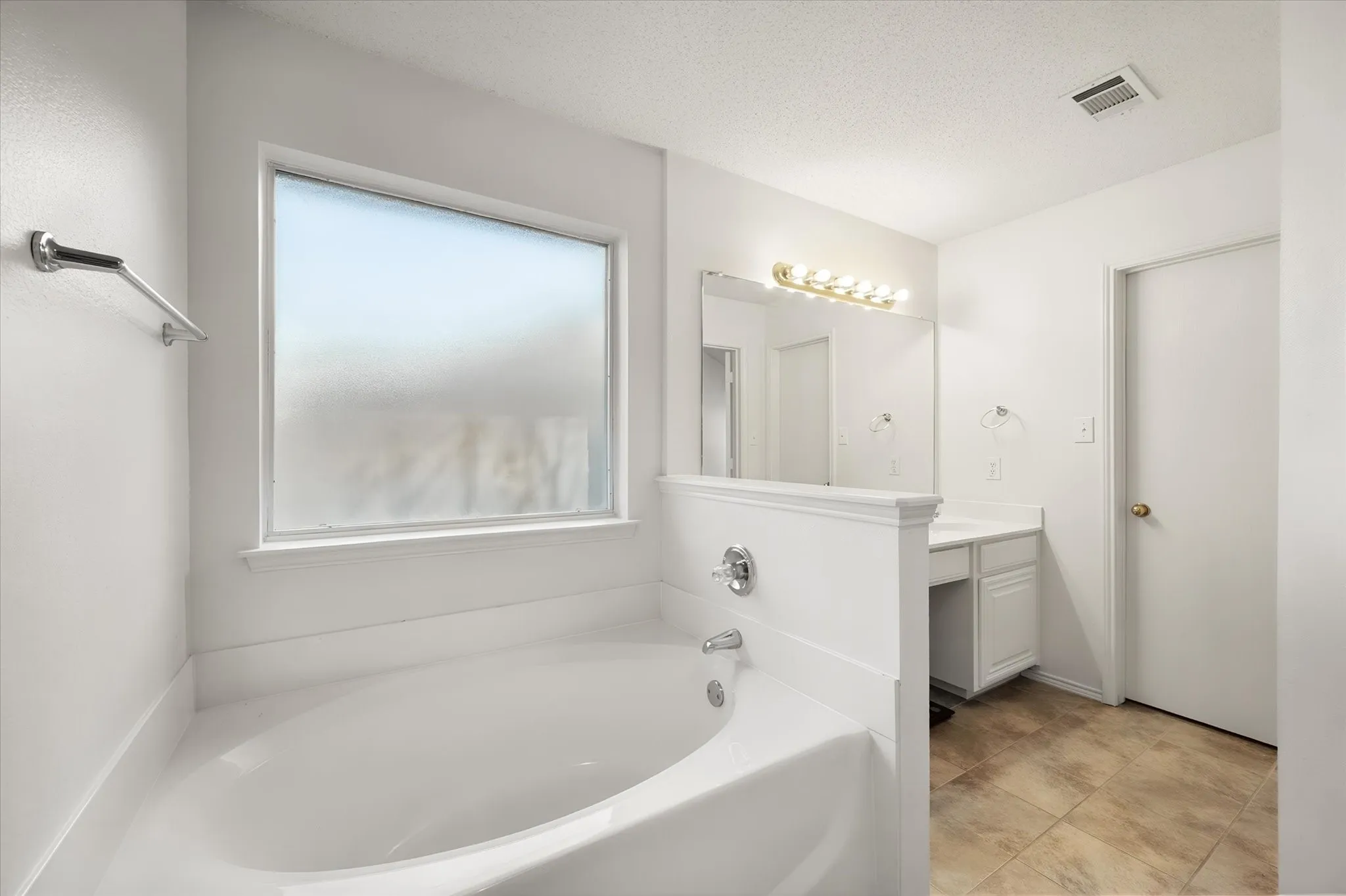 Built-in bathtub with chrome fixtures, frosted privacy window, and a white vanity with integrated sink and mirror