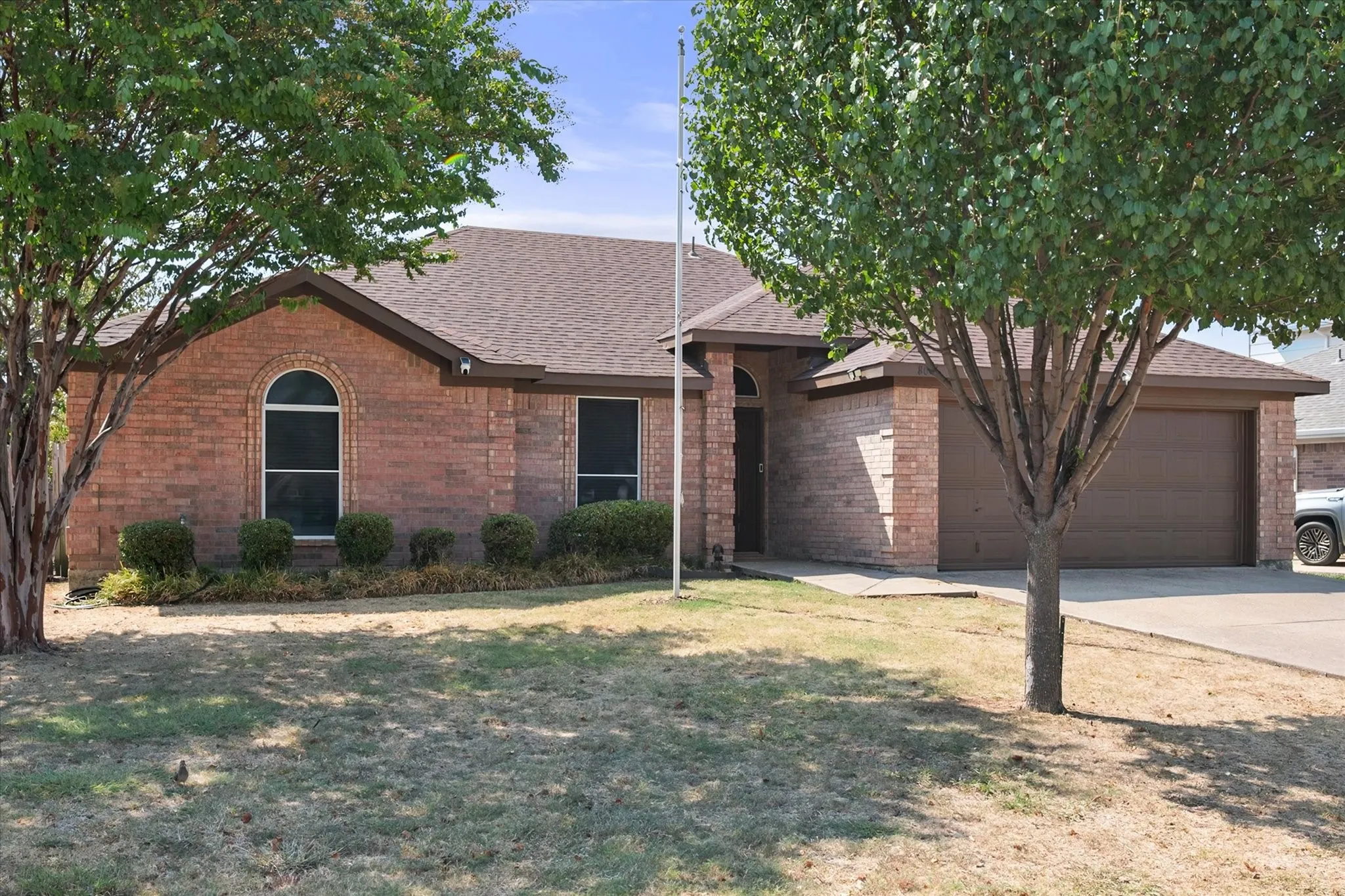 Red brick exterior with an arched window, a two-car garage, and a concrete driveway