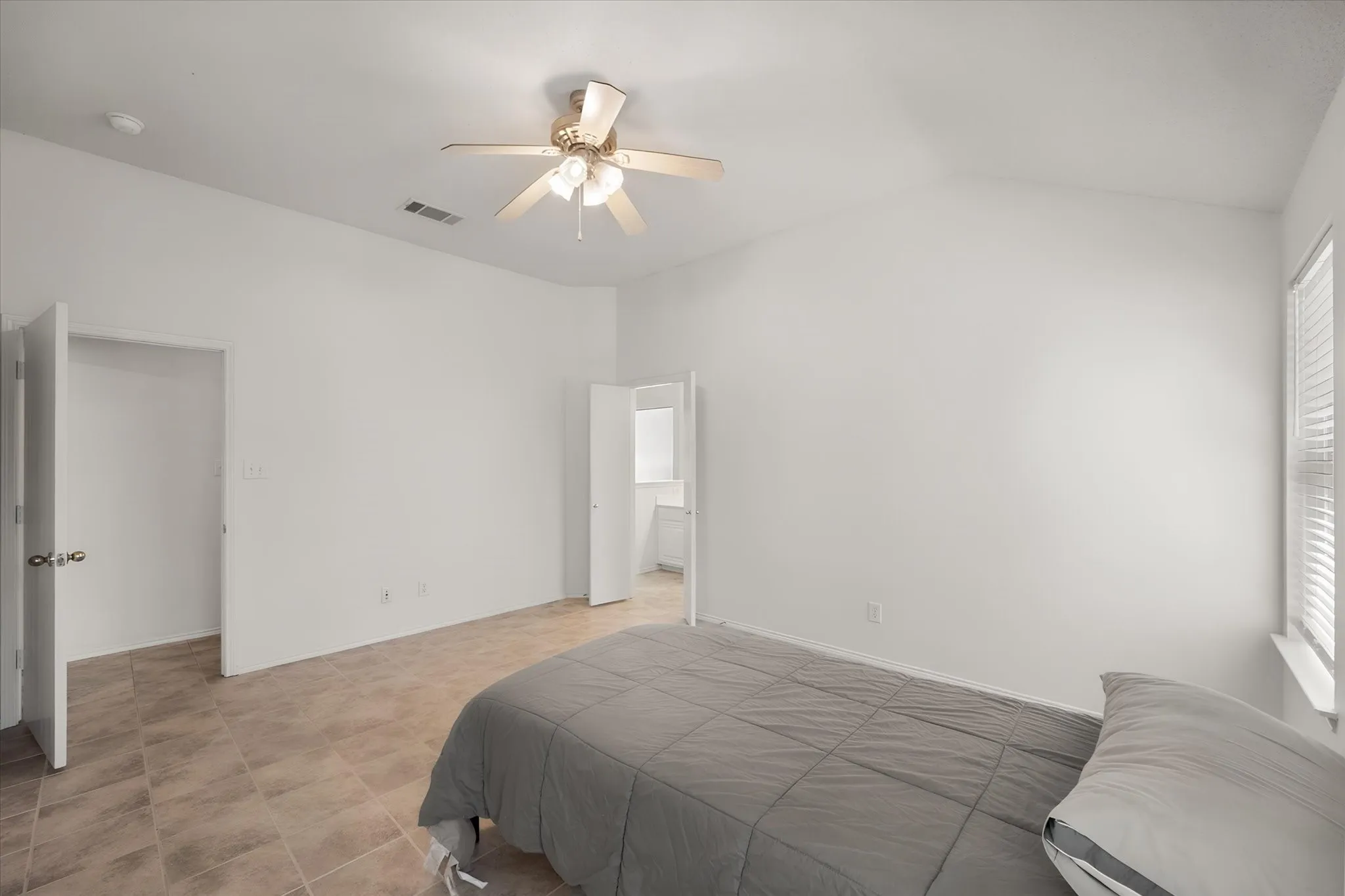Vaulted ceiling with a ceiling fan, tile flooring, window with blinds, and a built-in closet