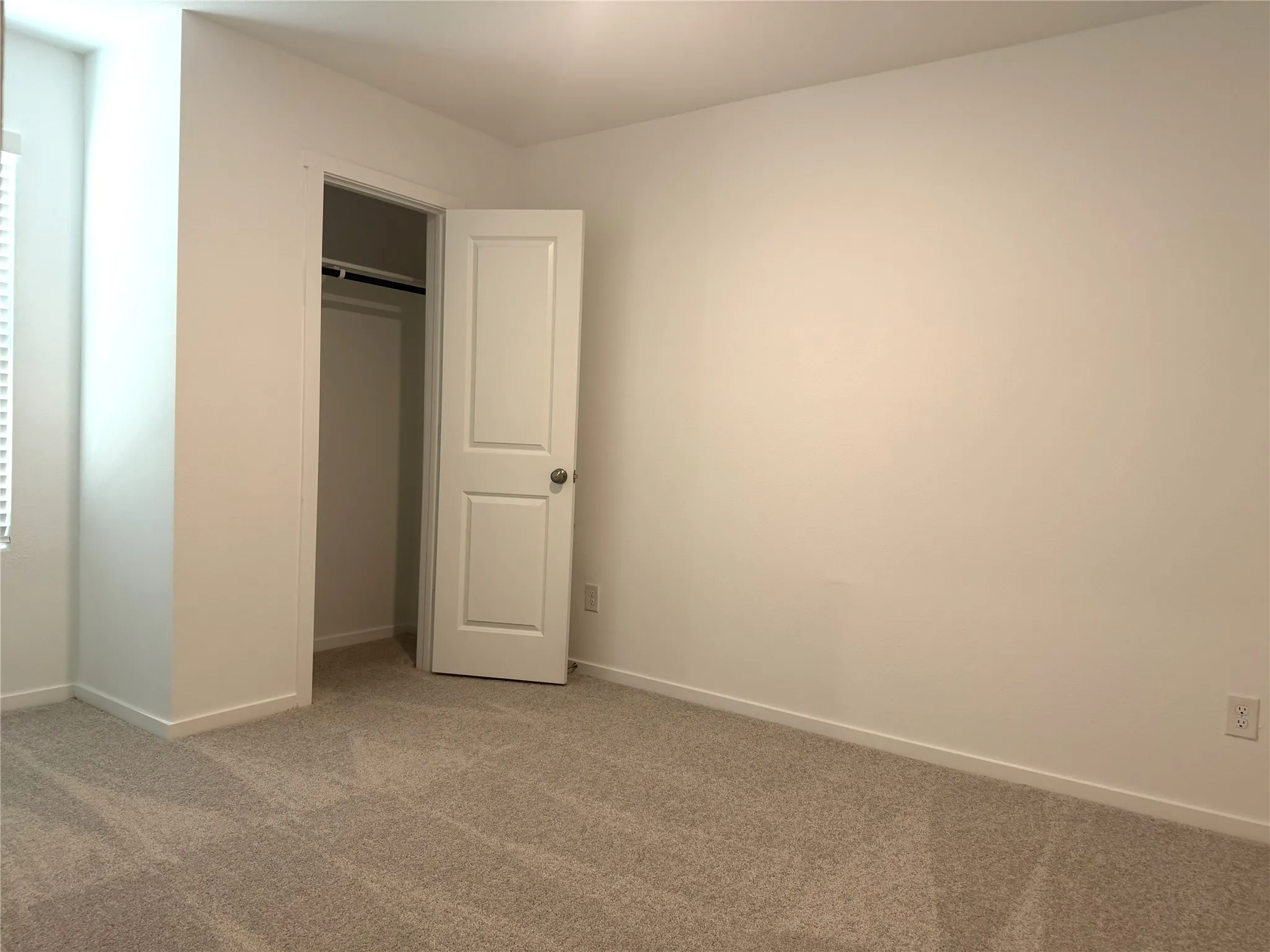 Recessed lighting, light-toned carpeting, white walls, white trim, and a white interior door