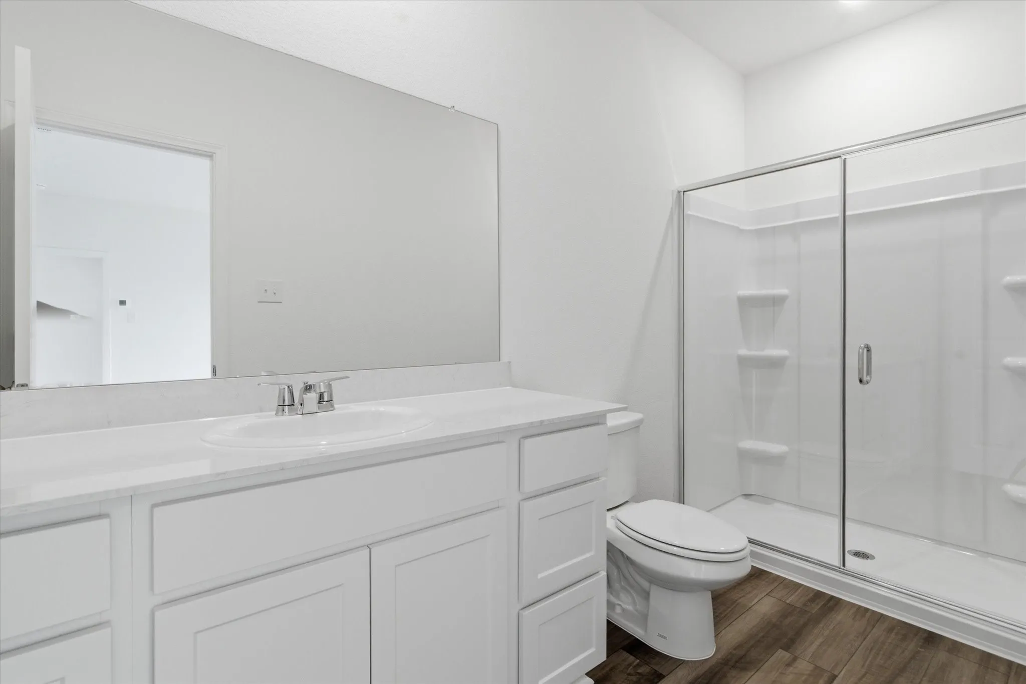 Bathroom featuring a white vanity with integrated sink, chrome faucet, and a large wall-mounted mirror