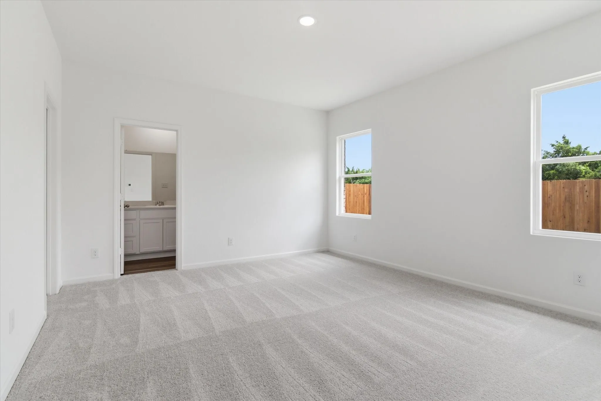 Bright interior with two windows, light gray carpet, and a recessed ceiling light