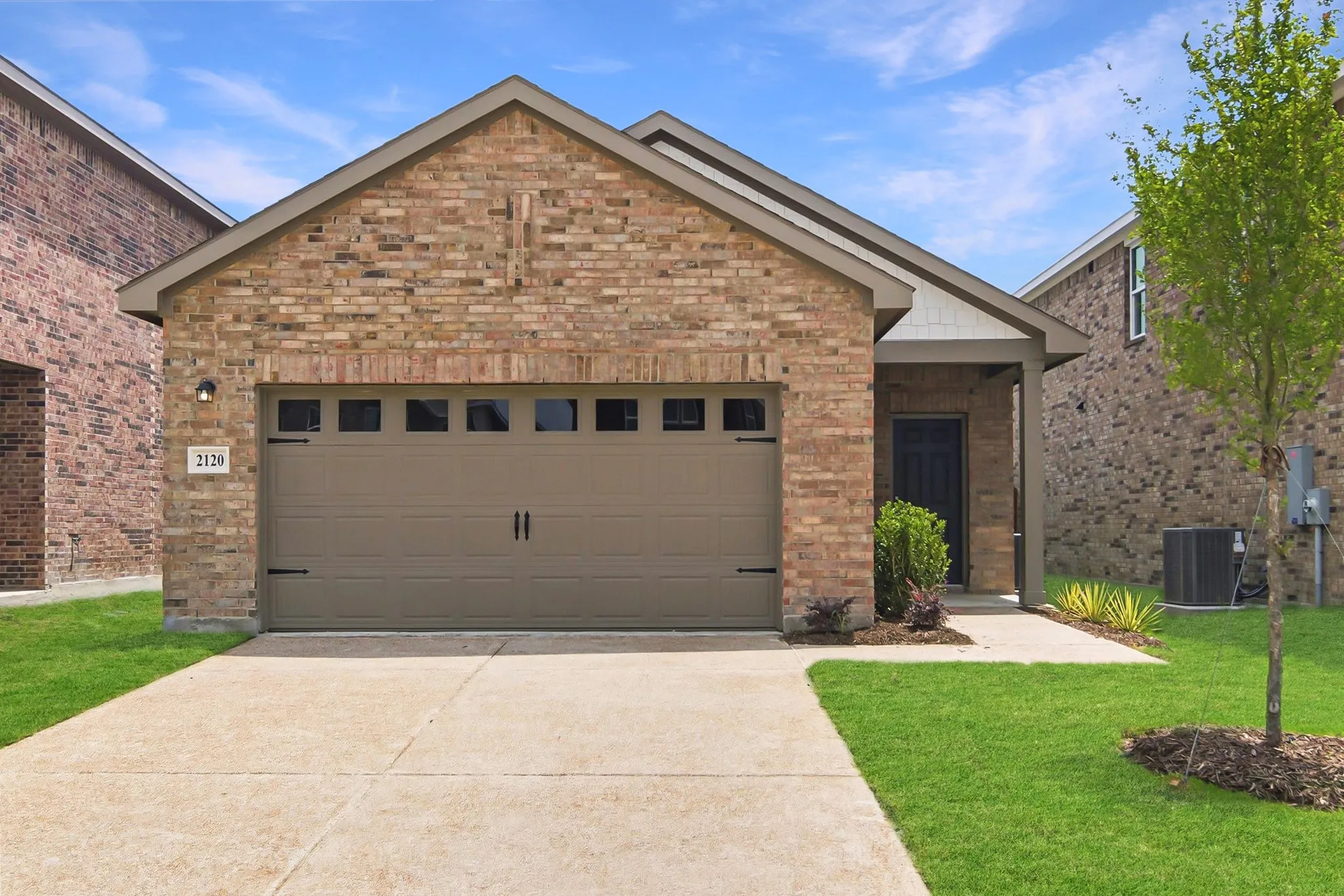 Brick veneer exterior with a covered entry, attached garage, and concrete driveway