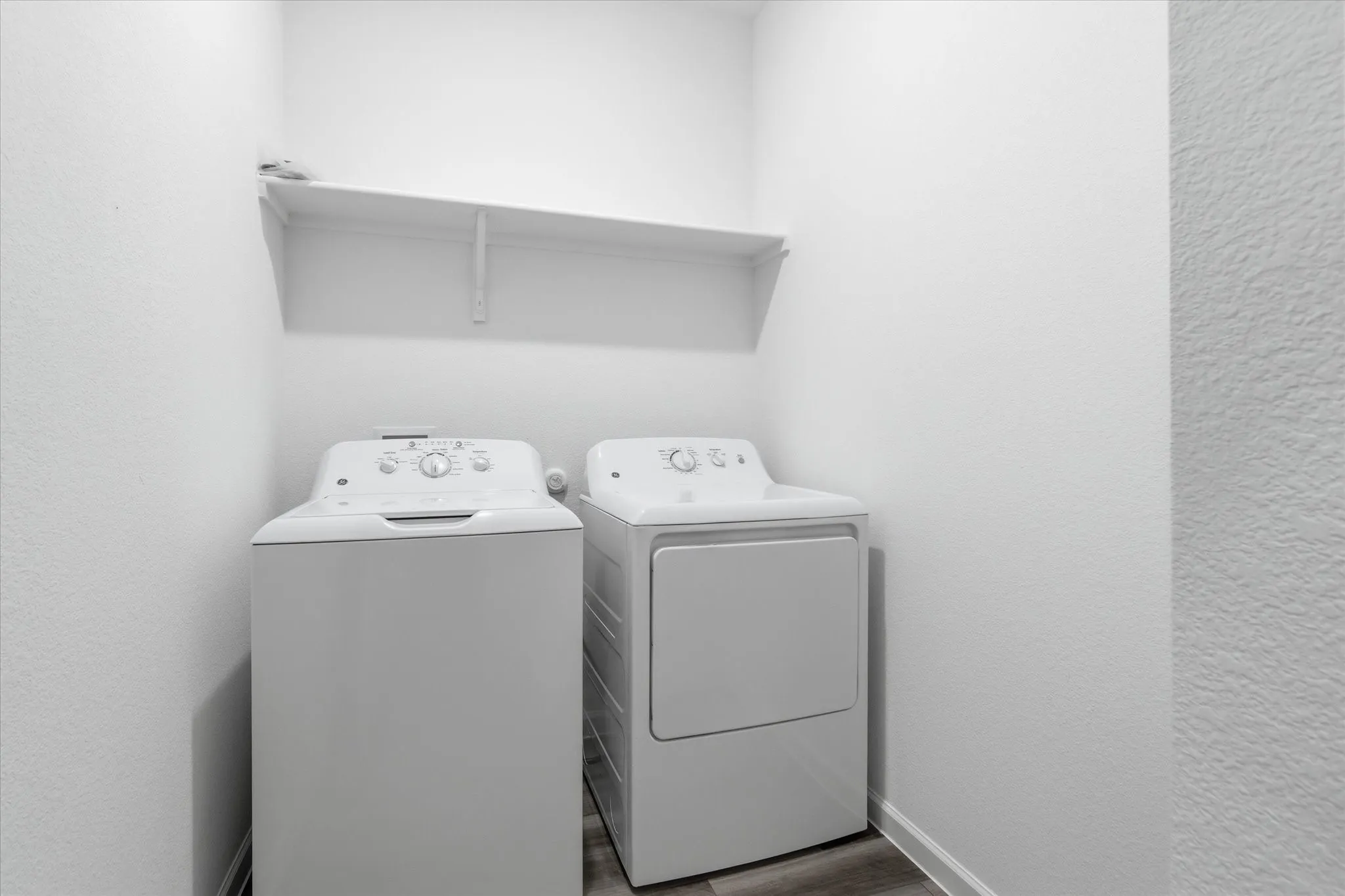 Laundry area with a built-in shelf and wood-finish flooring