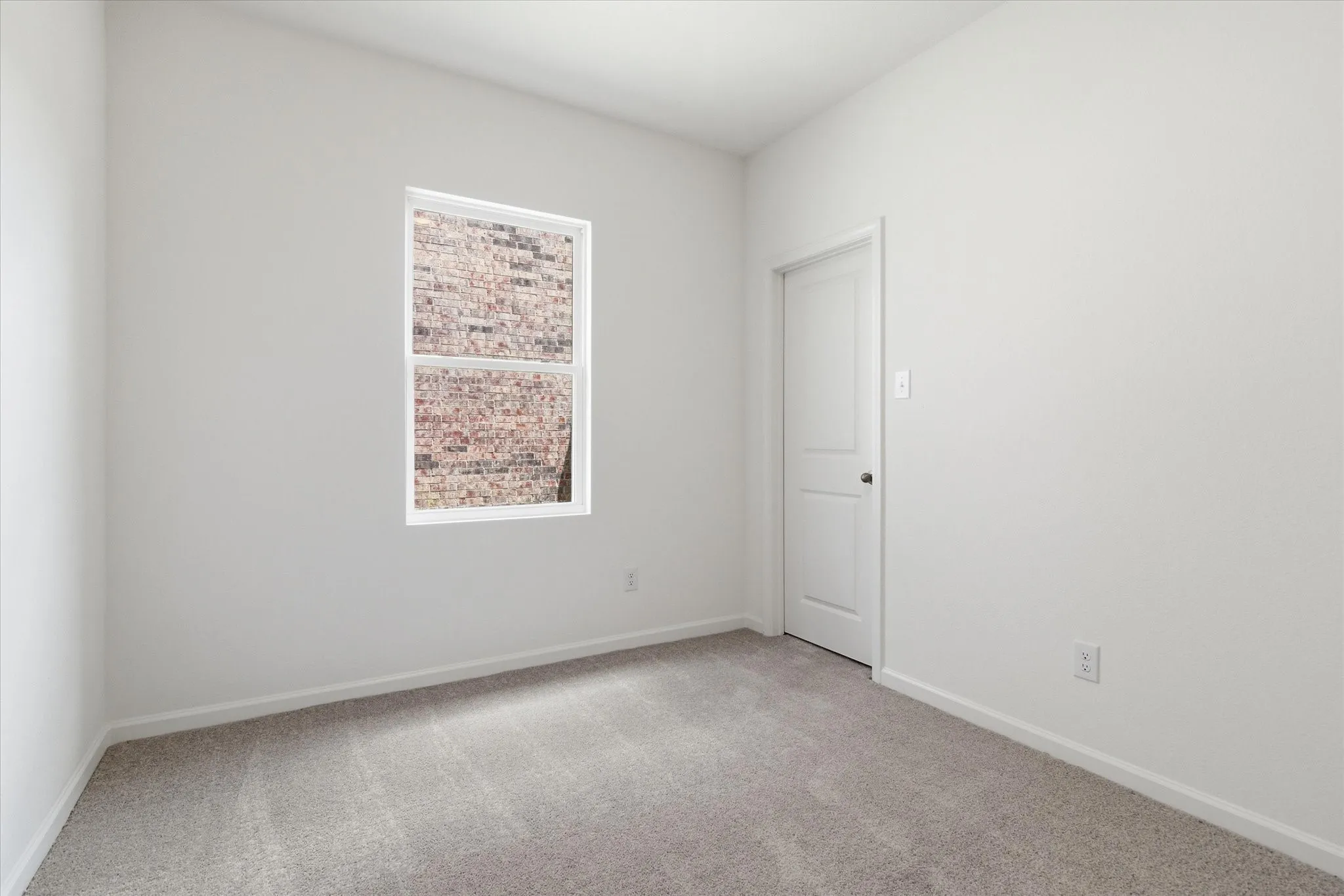 Recessed window with white trim, light gray wall-to-wall carpeting, and white painted walls