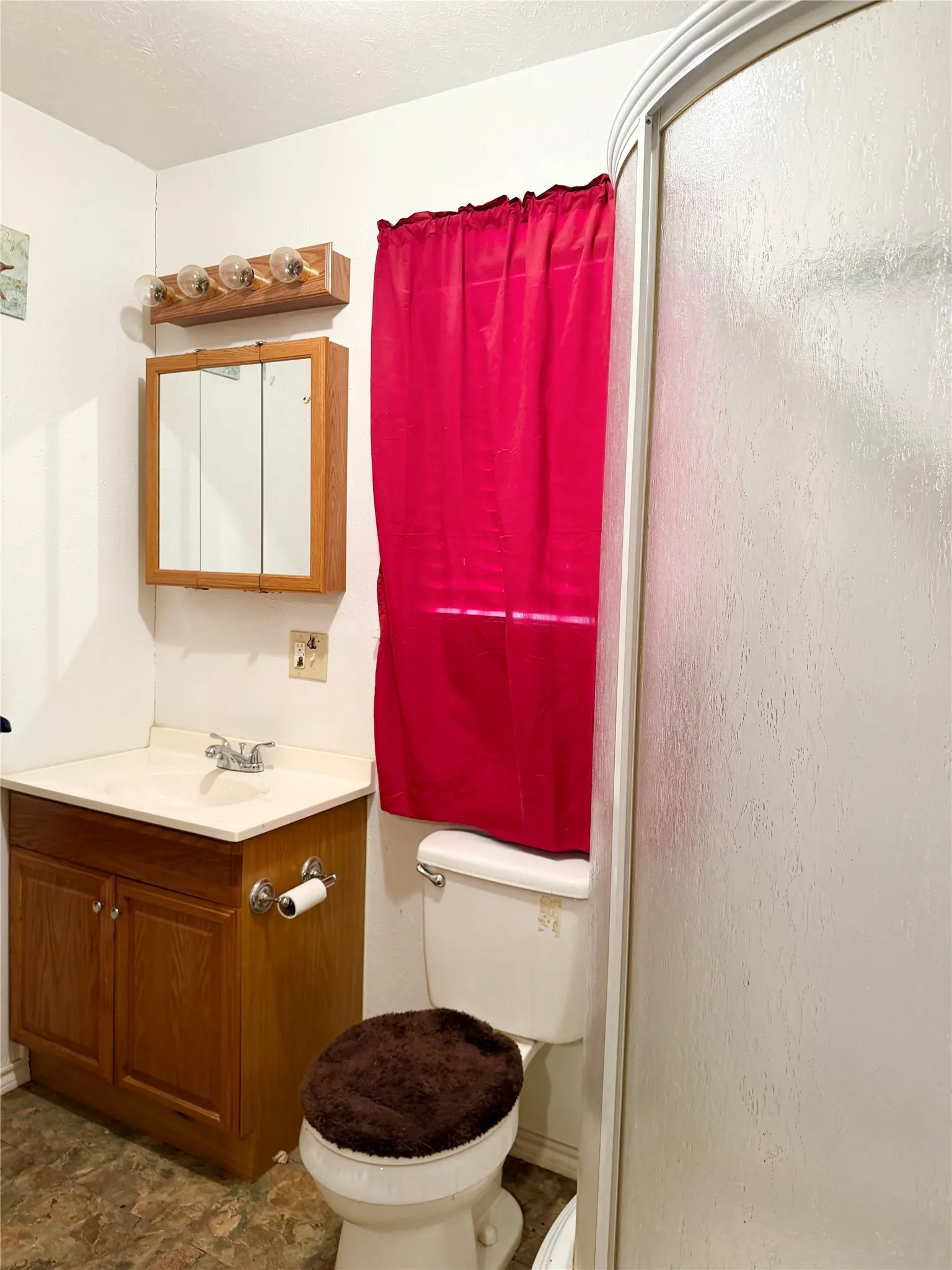 Wood-finish vanity with an integrated sink, medicine cabinet, and a shower enclosure