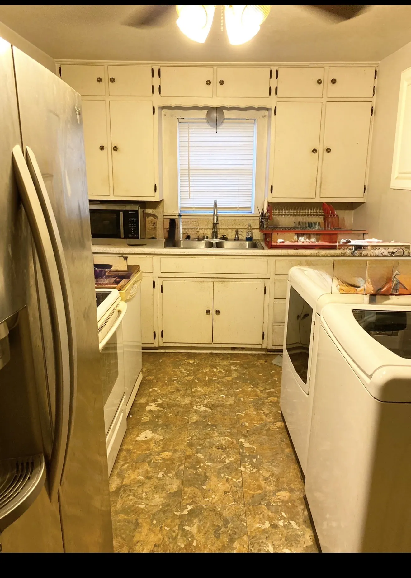 Kitchen featuring upper and lower cabinetry, a double basin sink with a chrome faucet, and a window with blinds