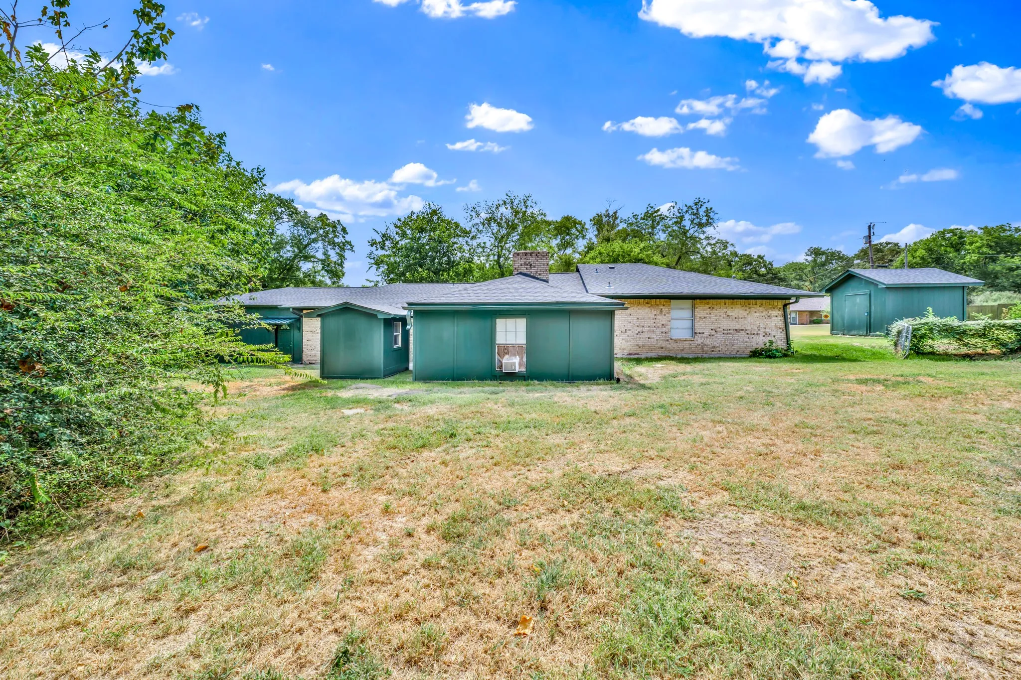 large yard , showing back of home and other storage to the right
