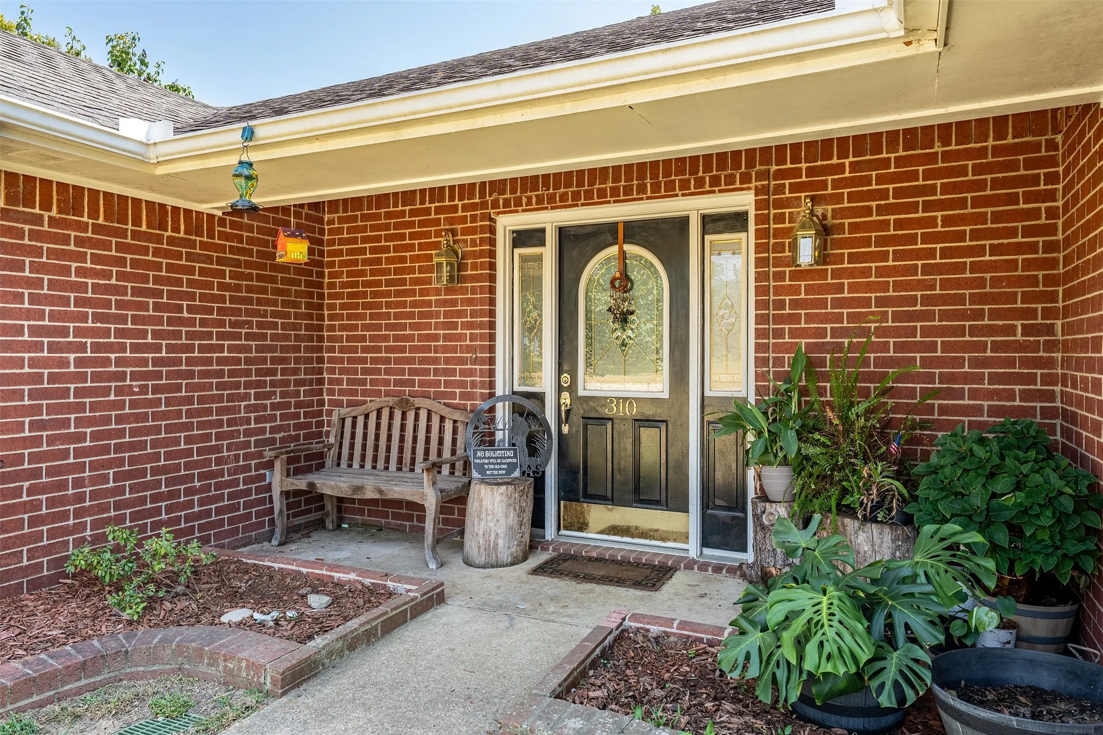 Brick exterior, covered entry, and decorative glass entry door with sidelights