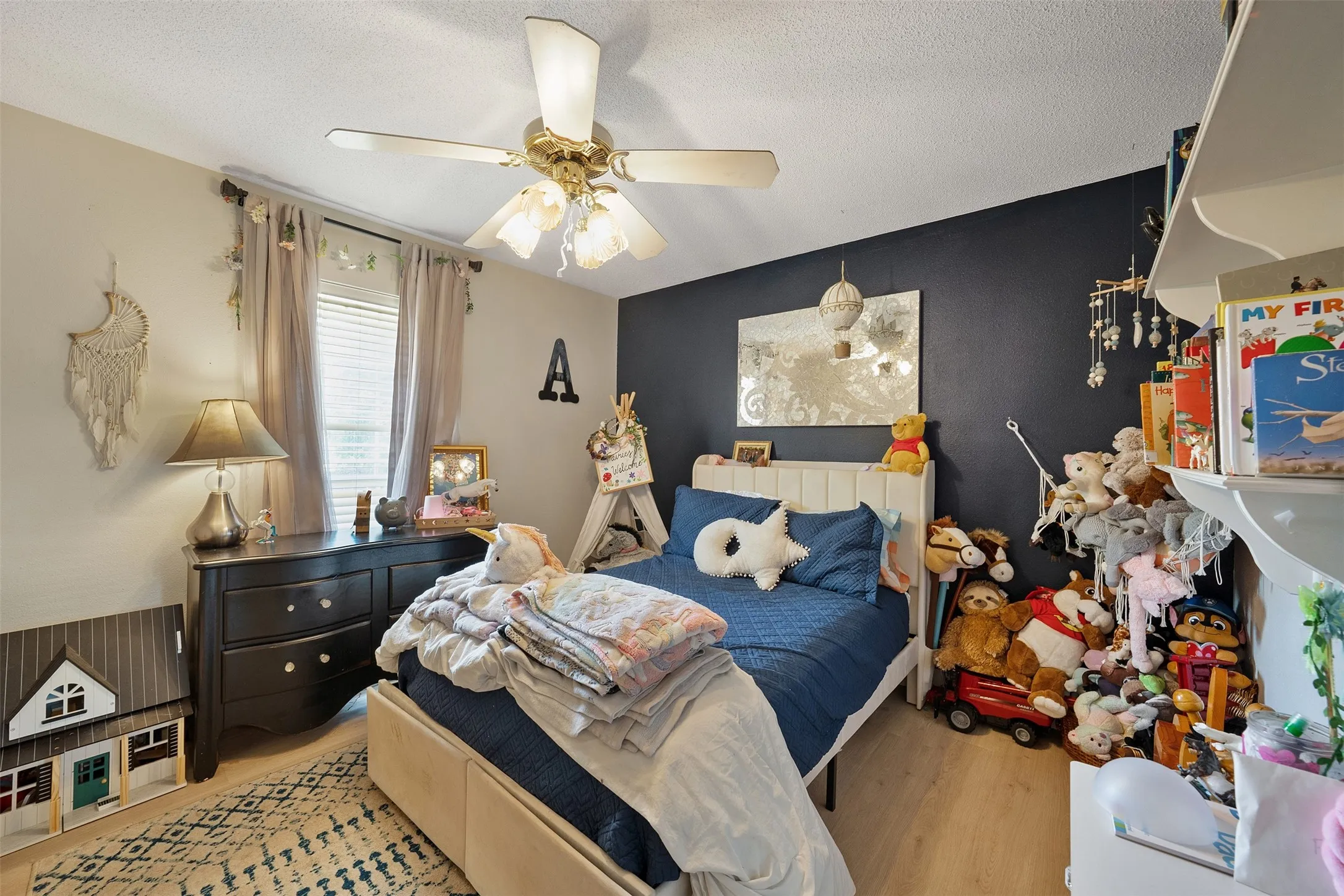 Recessed window with blinds, overhead ceiling fan with light fixture, wood-finish flooring, and built-in shelving