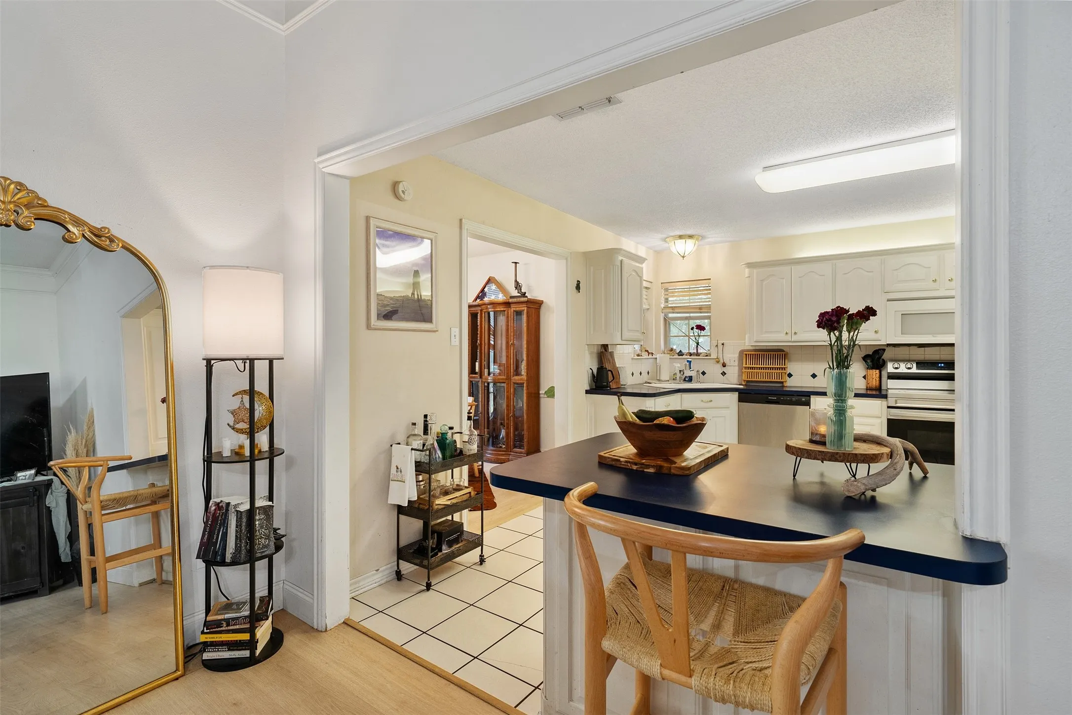 Kitchen featuring white cabinetry, stainless steel appliances, a built-in oven, and a breakfast bar with a solid surface countertop