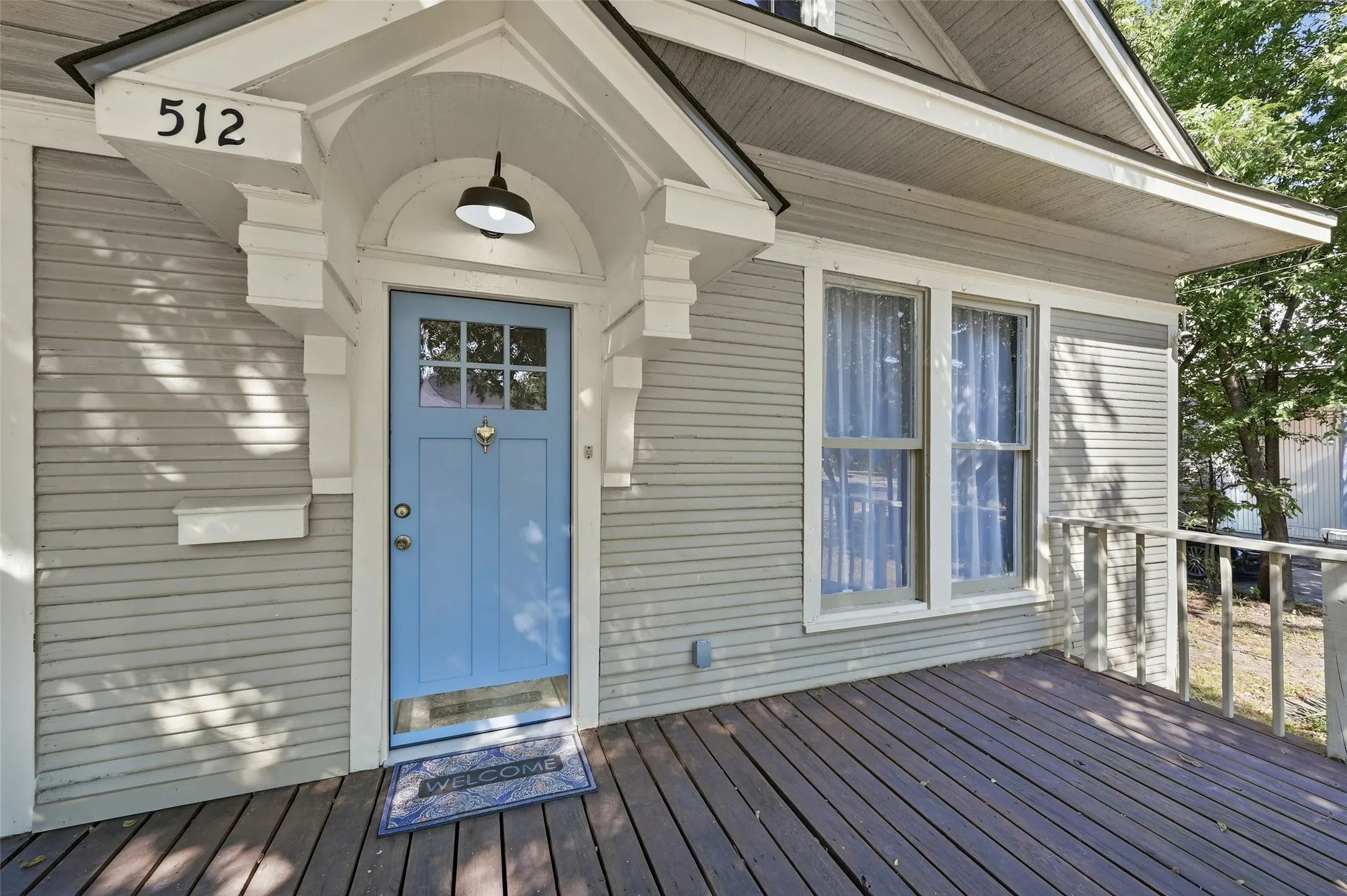 Inviting front porch with plank flooring, a light blue paneled door with glass inserts, and a decorative door knocker