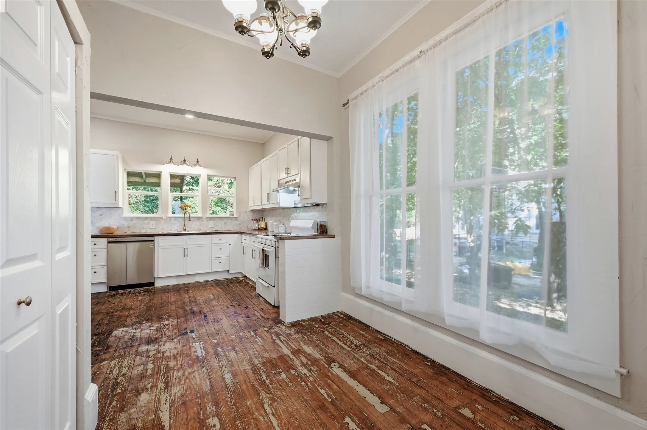 Bright kitchen area featuring white cabinetry, stainless steel appliances, and a vaulted ceiling