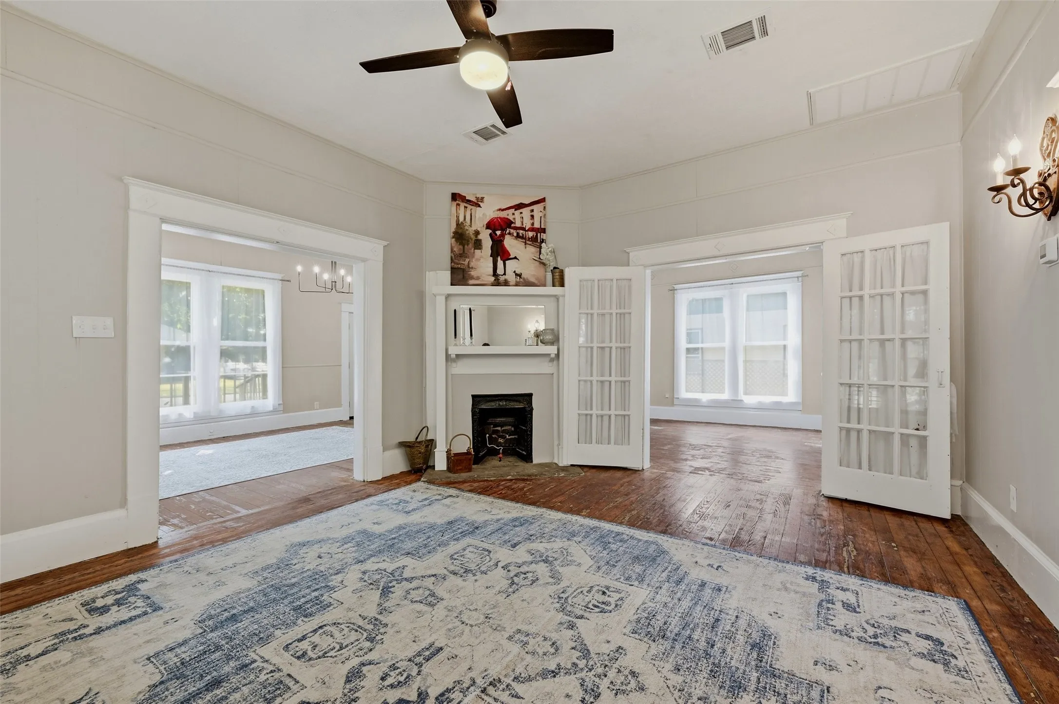Hardwood flooring, white trim, ceiling fan, fireplace with mantel, and French doors