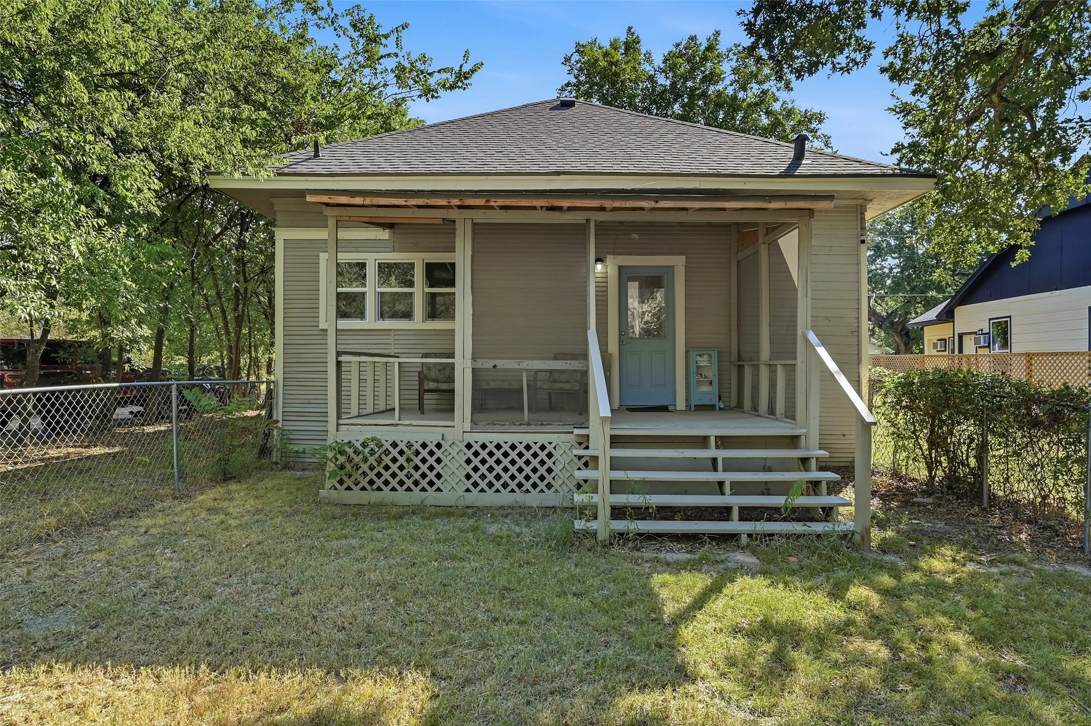 Front porch with wood railing and steps, lattice detailing, and a light blue entry door