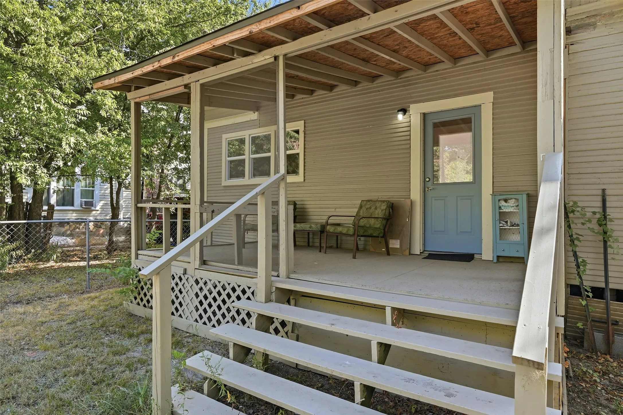 Covered front porch with concrete flooring and a light blue entry door